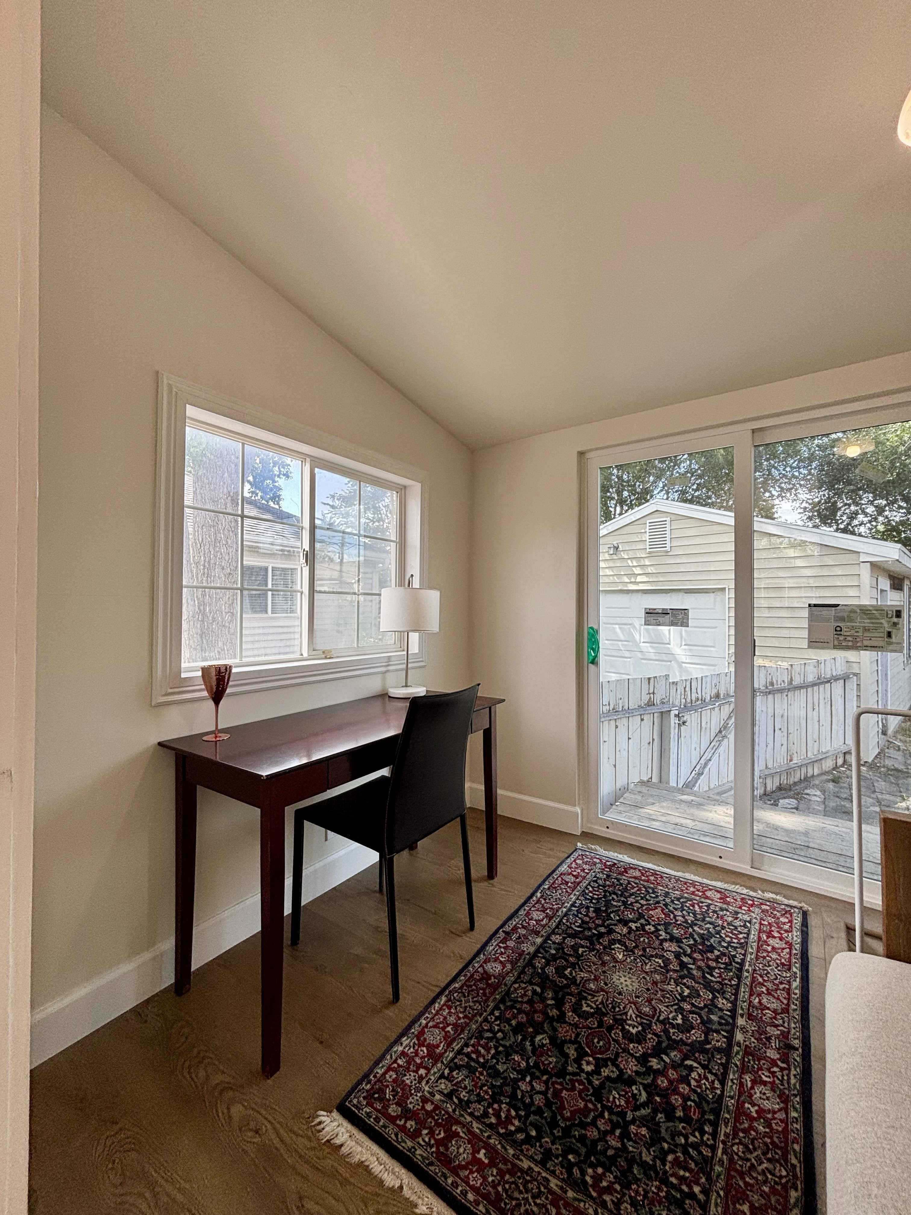Room featuring wood-finish flooring, a vaulted ceiling, and white baseboards