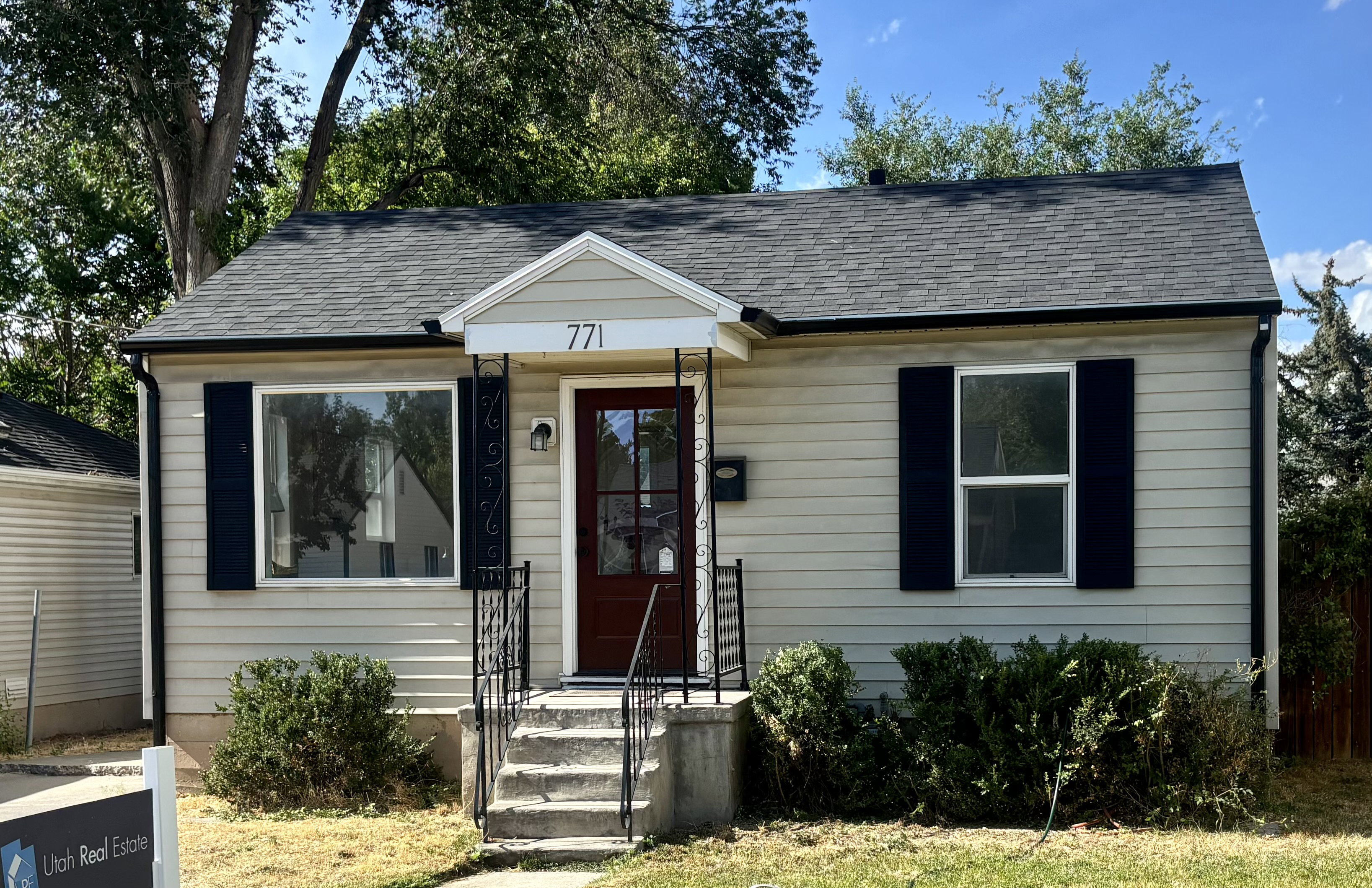 Single-story residence featuring light-colored siding, a dark asphalt shingle roof, and a prominent front entry with a dark-stained door