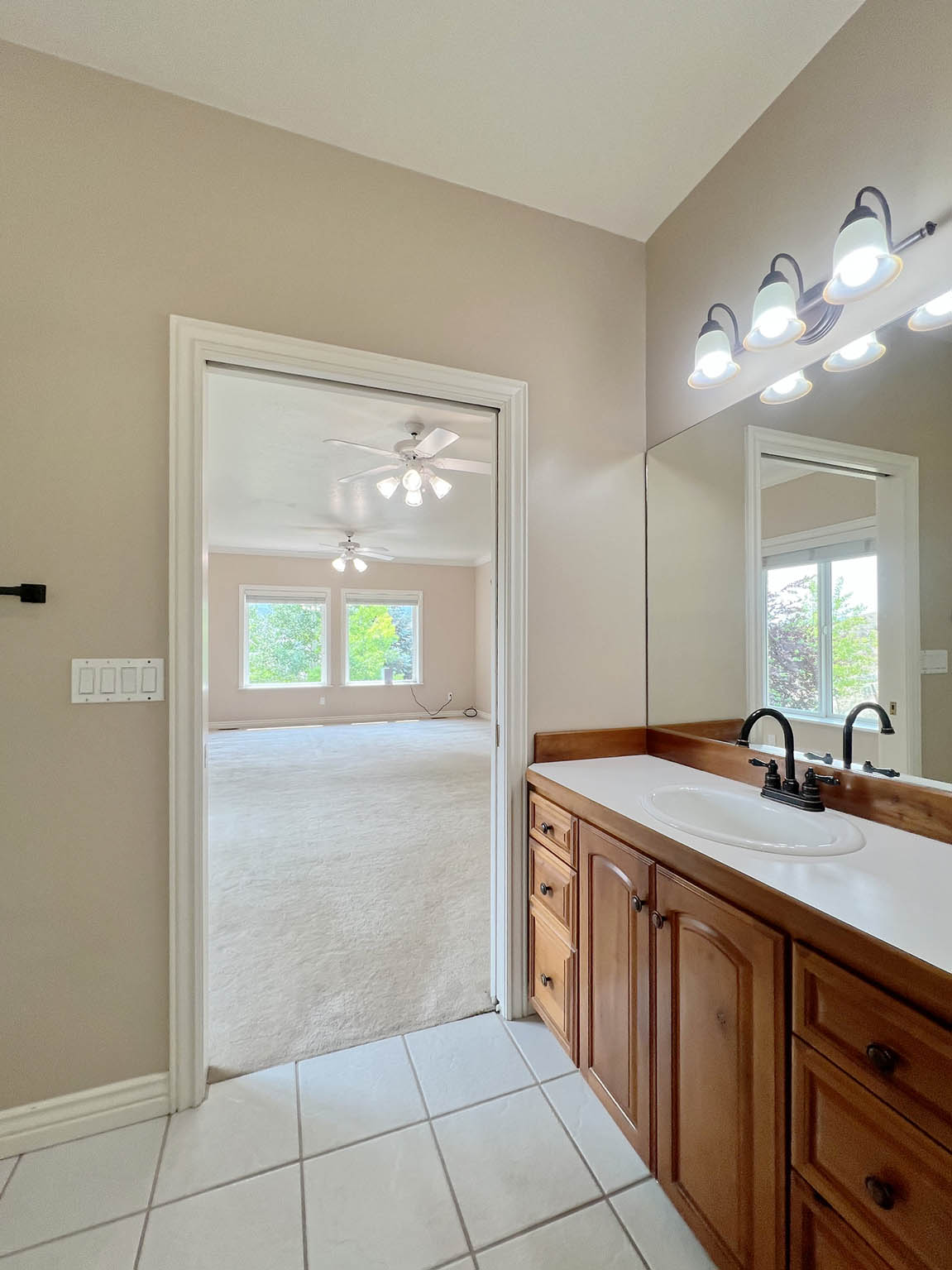 Bathroom vanity featuring wood cabinetry with black hardware, a white integrated sink, and black faucet