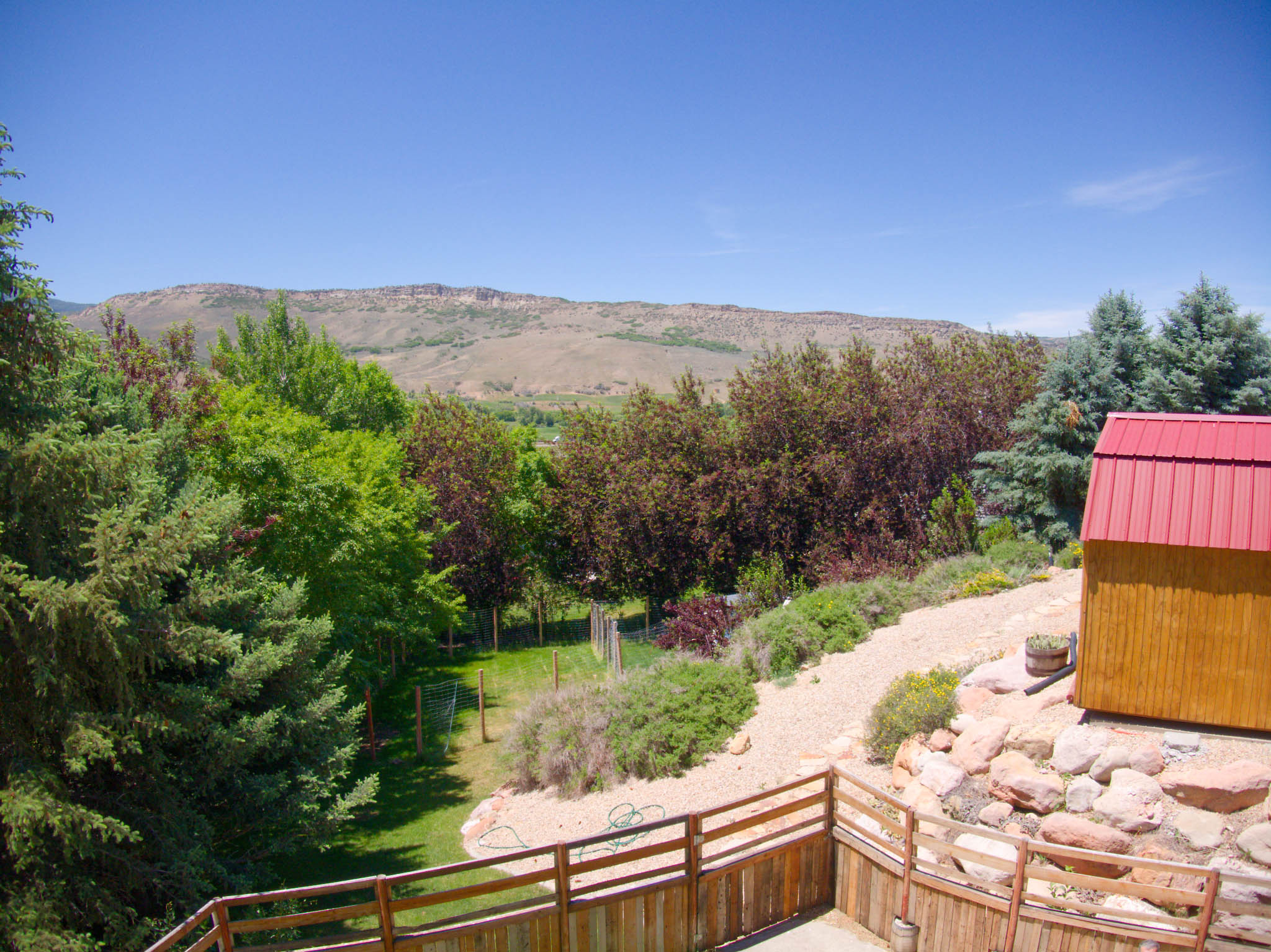 Expansive terraced yard with a natural wood fence and a gravel pathway