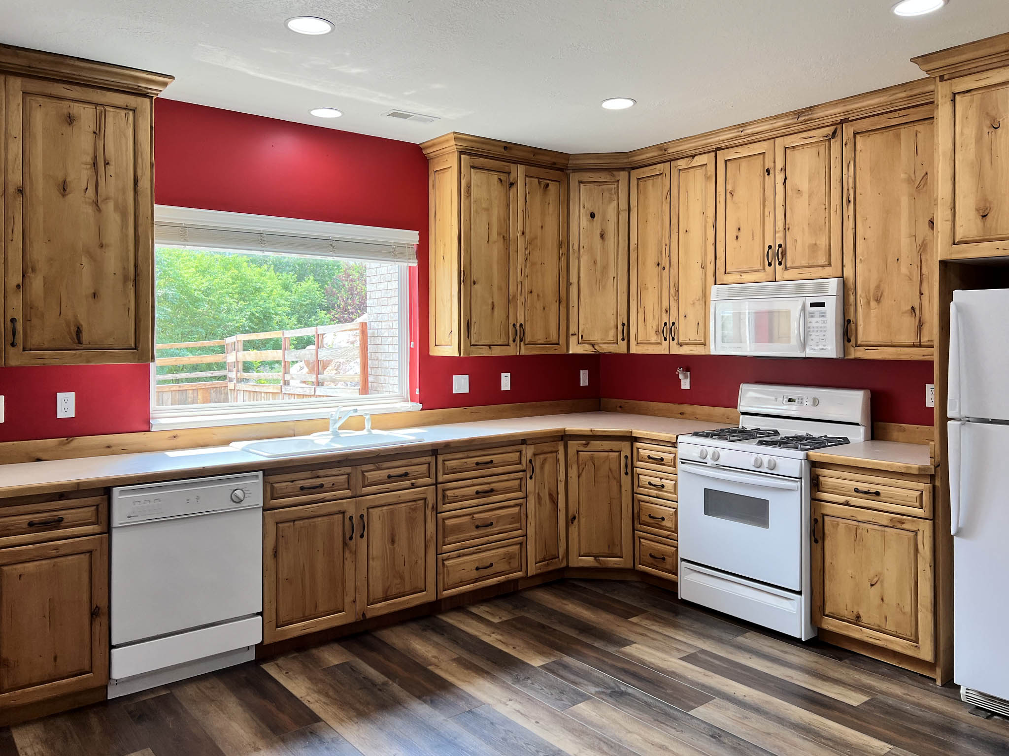 Spacious kitchen featuring extensive wood cabinetry, white appliances, and wood-finish flooring