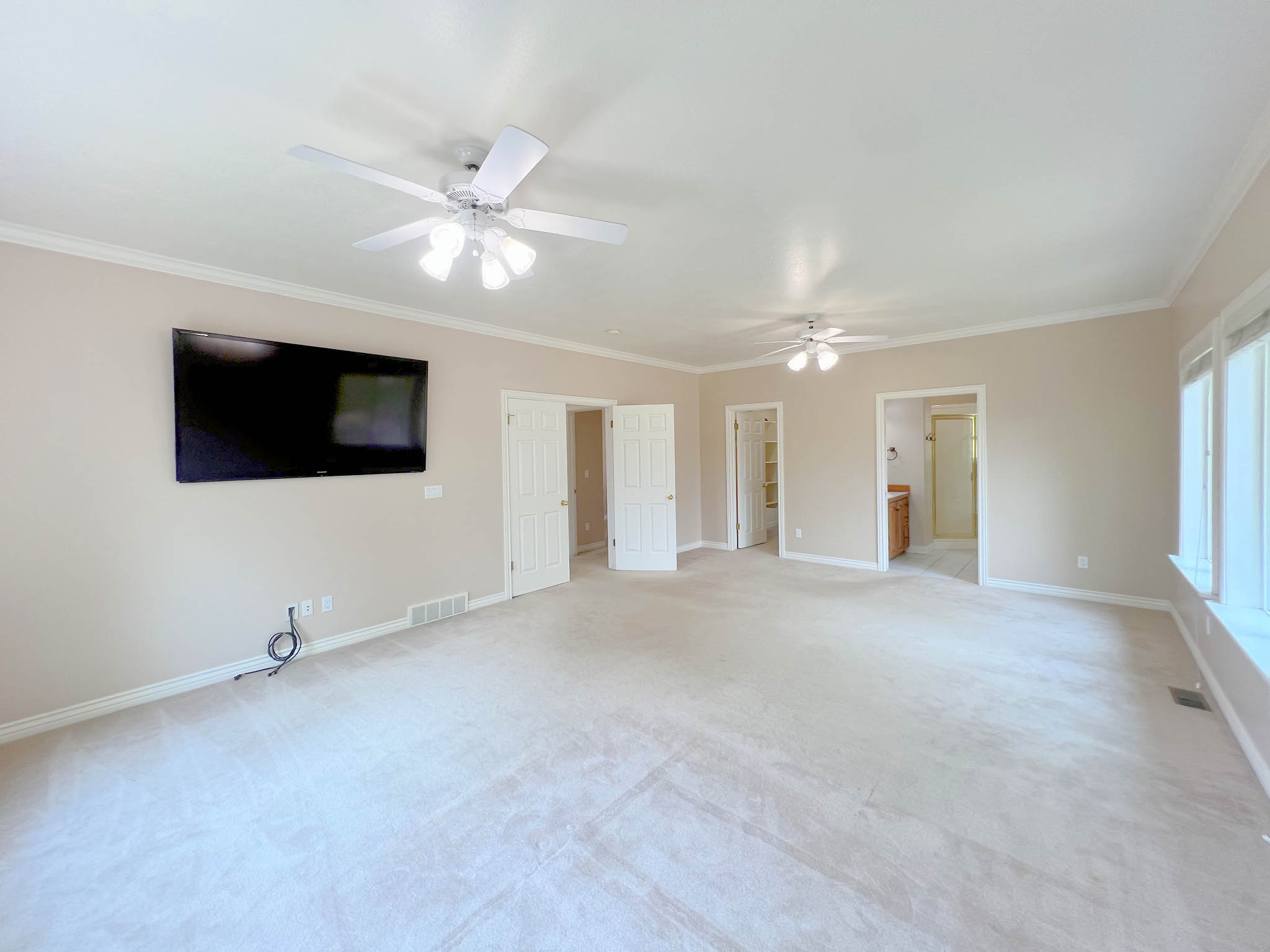 Spacious interior room featuring light-toned carpeting and neutral wall tones