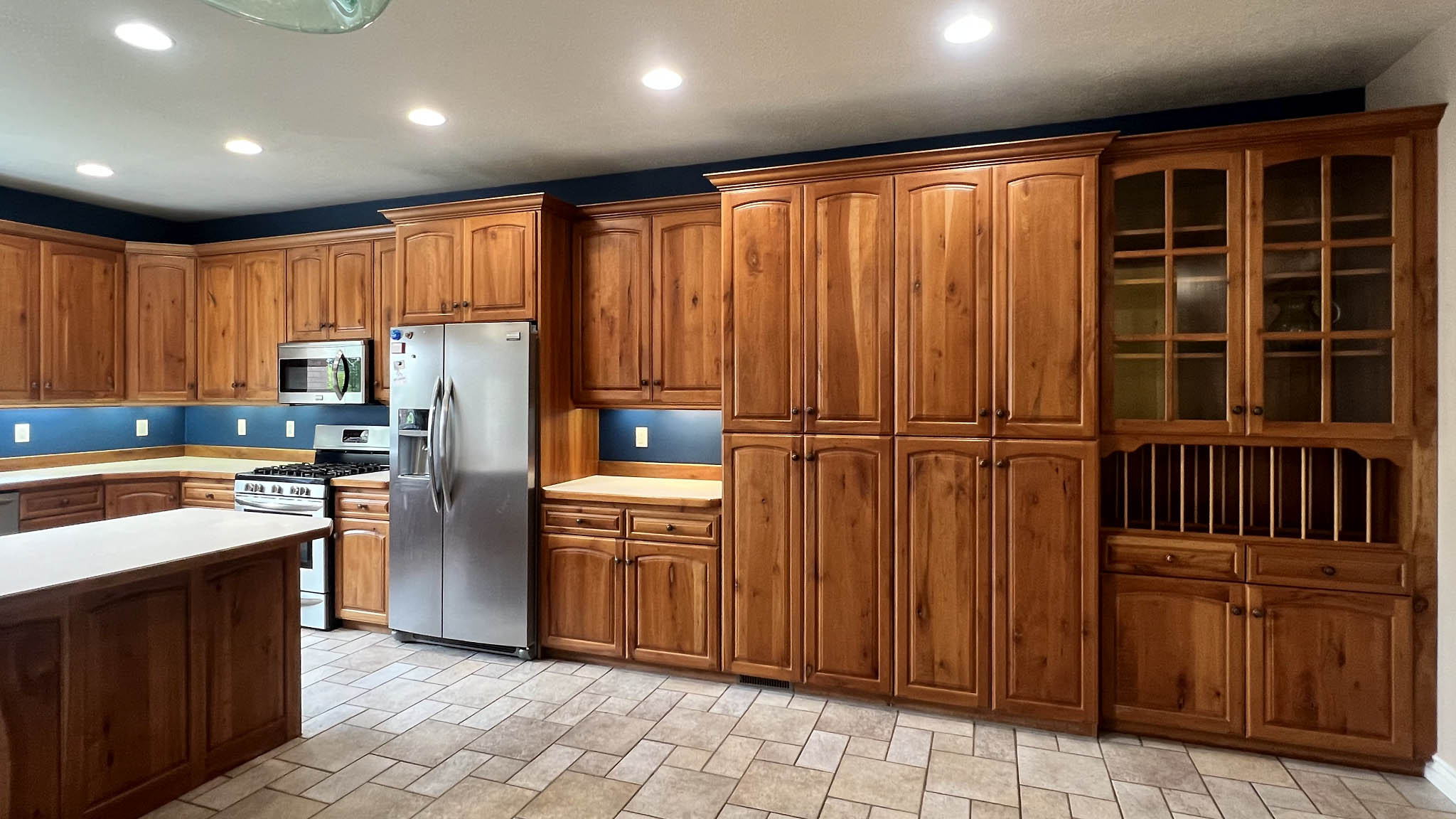 Spacious kitchen featuring extensive wood cabinetry, tile flooring, stainless steel appliances, a kitchen island, and recessed lighting