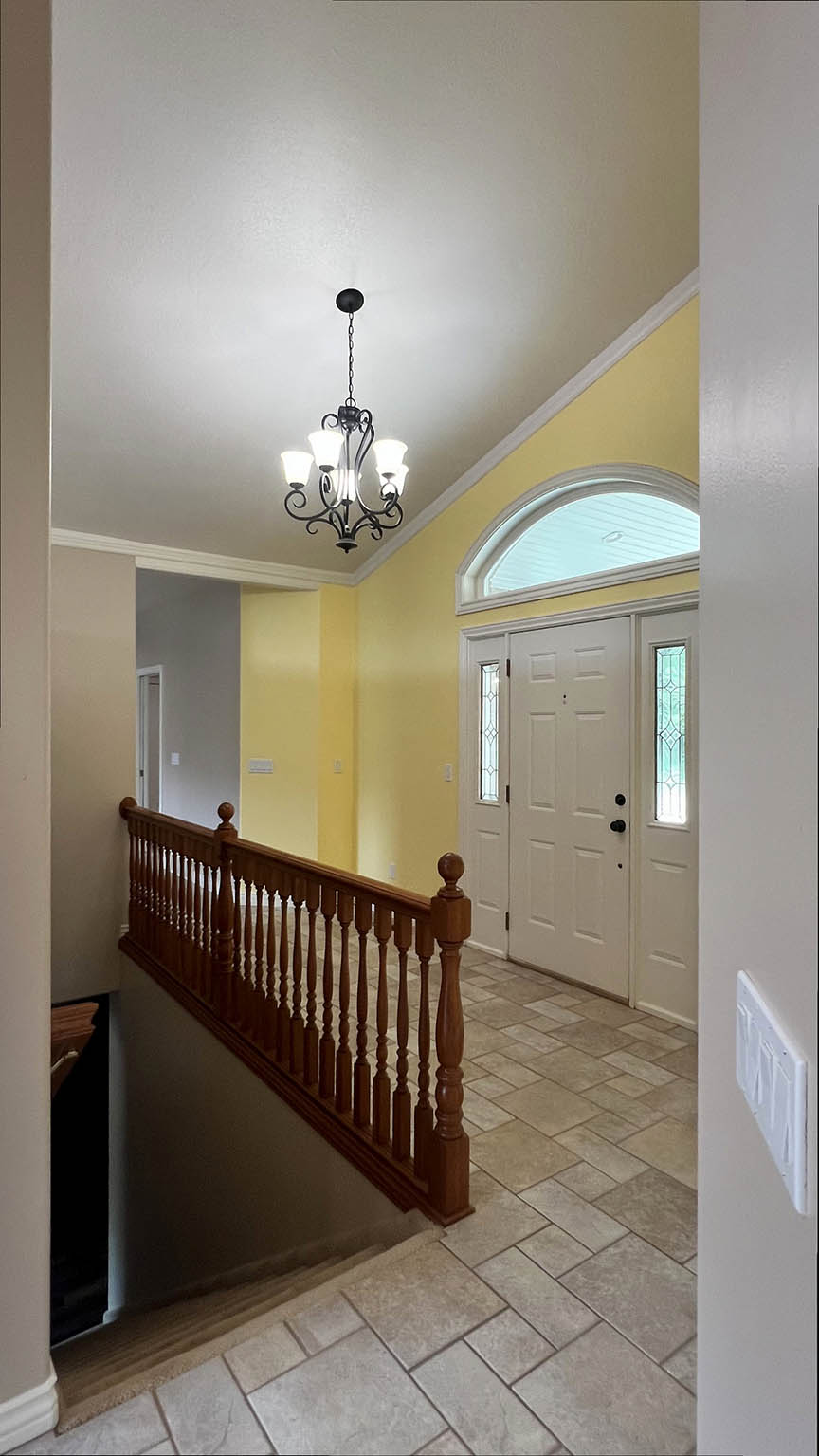 Entryway featuring a decorative chandelier, vaulted ceiling, and a wooden banister