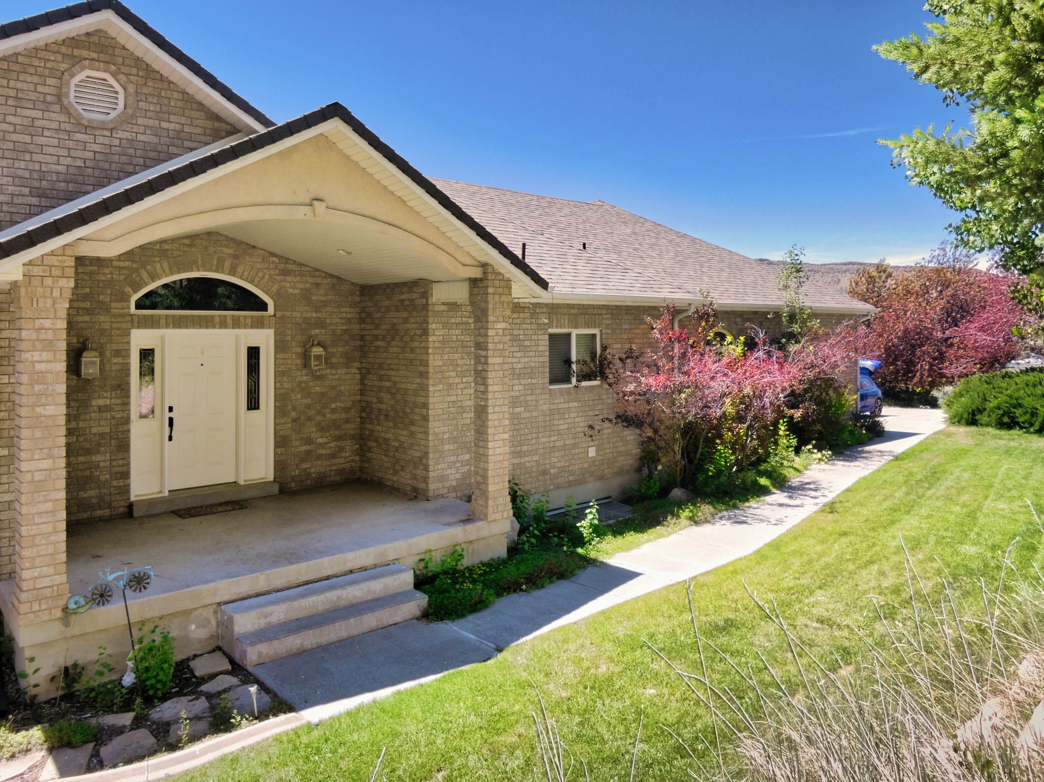 Brick exterior featuring an arched entryway with a white door and sidelights, covered porch, and gabled roofline