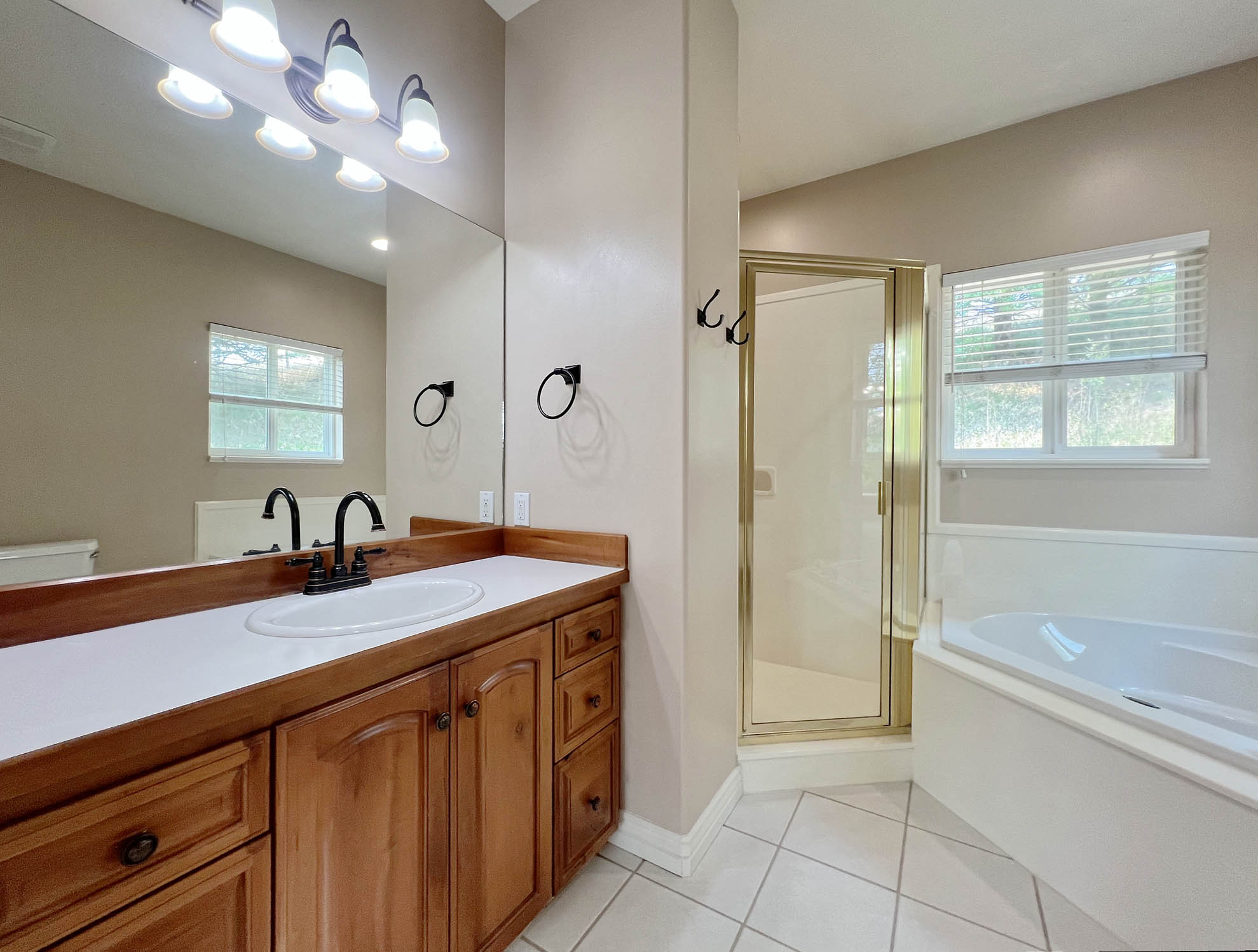 Bathroom featuring a wood-finish vanity with an integrated sink, a large wall mirror, and a three-light fixture