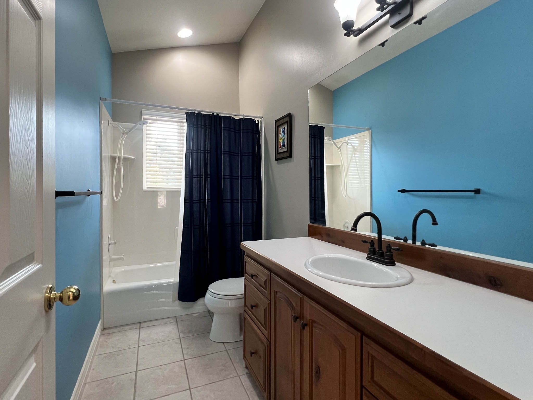 Bathroom featuring a wood-finish vanity with a white countertop, an undermount sink, and dark bronze-finish fixtures
