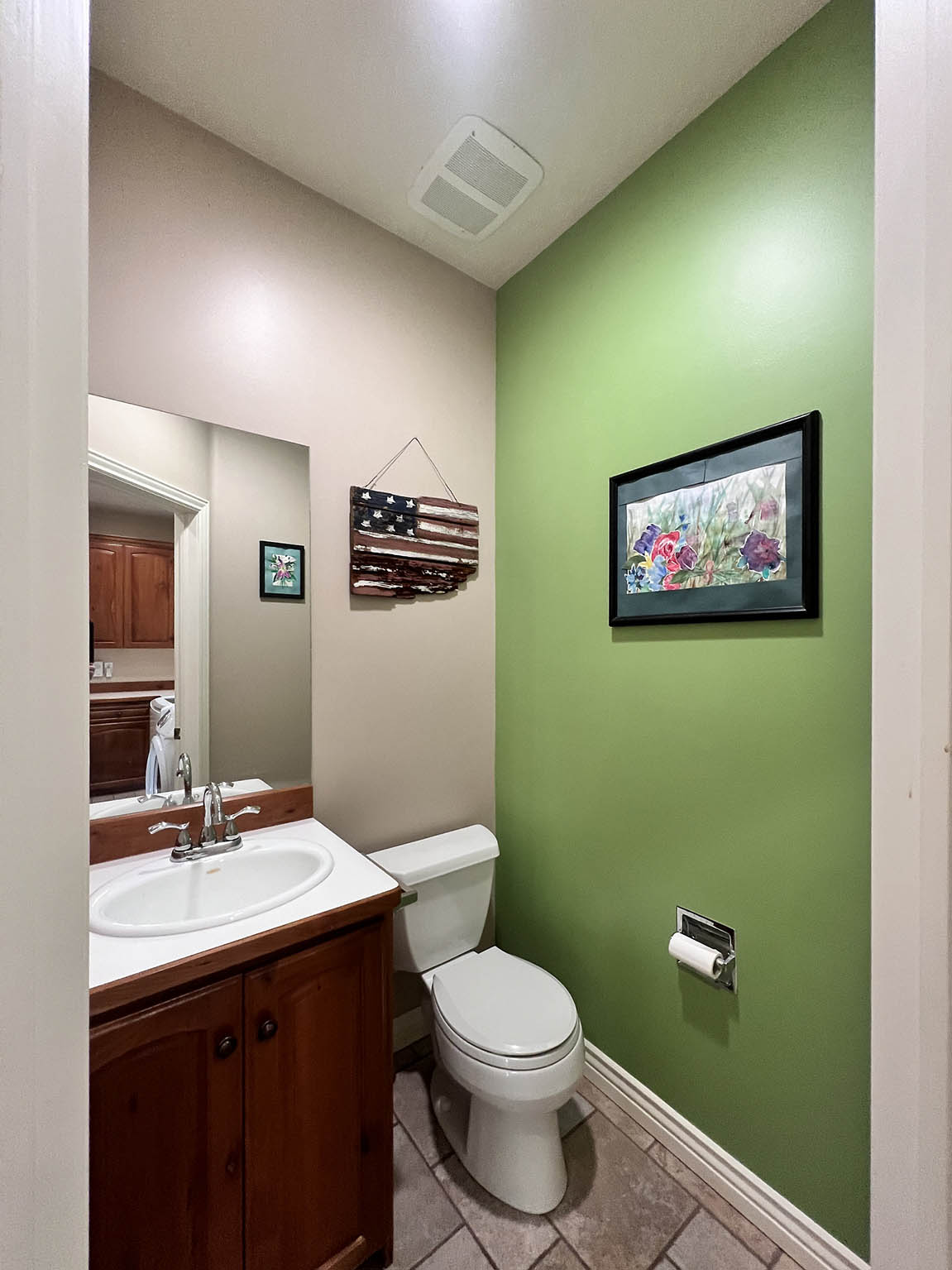 Powder room featuring a single vanity with wood-finish cabinetry, a white basin sink, chrome faucet, and a toilet