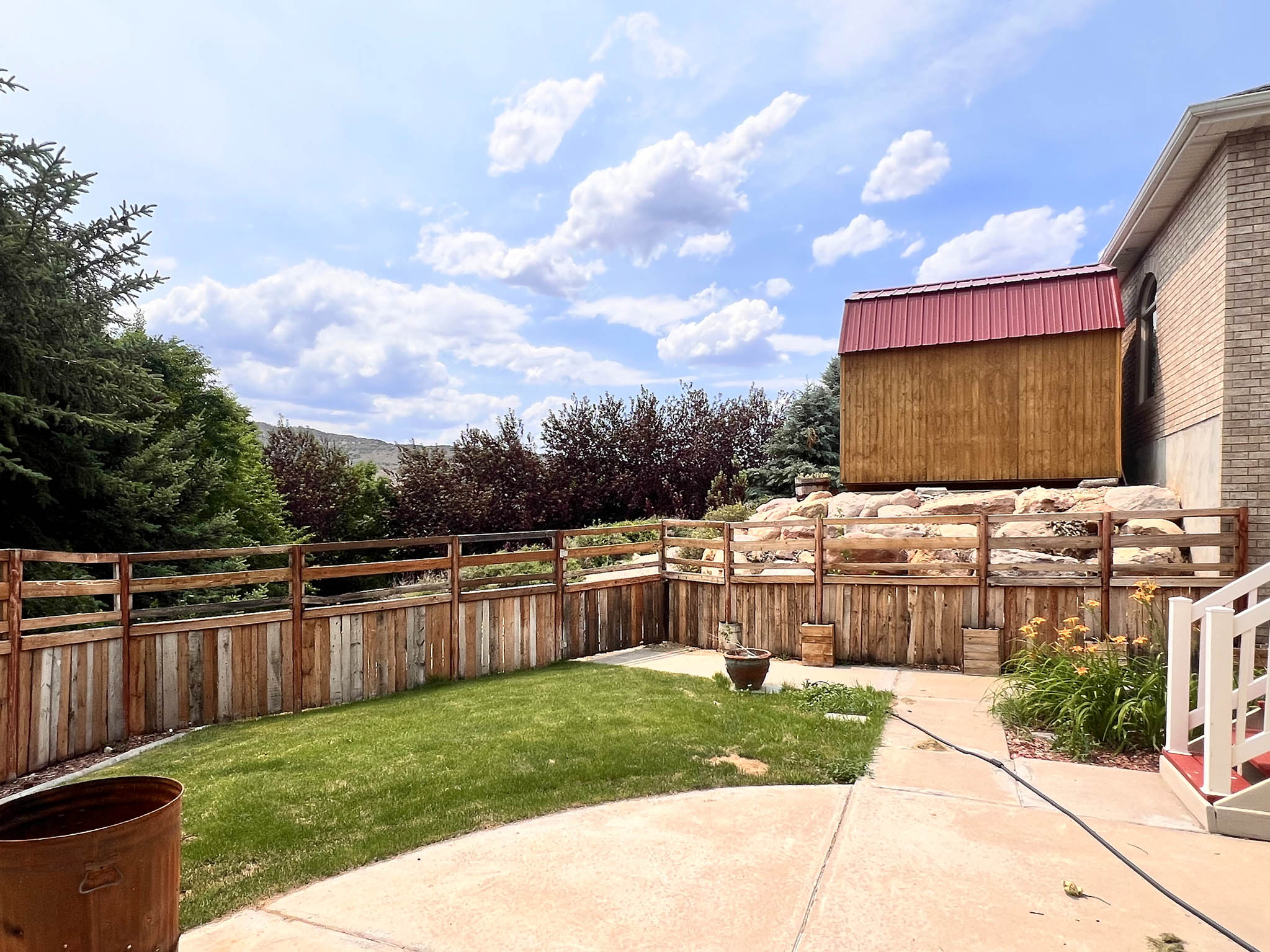 Expansive backyard featuring a manicured lawn, a half-privacy wood fence, and a concrete patio