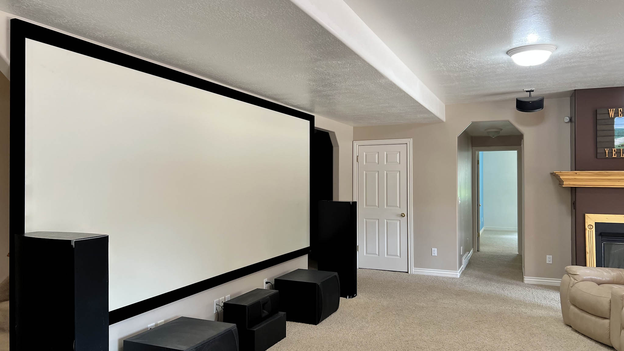 Dedicated entertainment space featuring a large projection screen, neutral carpeting, and recessed lighting