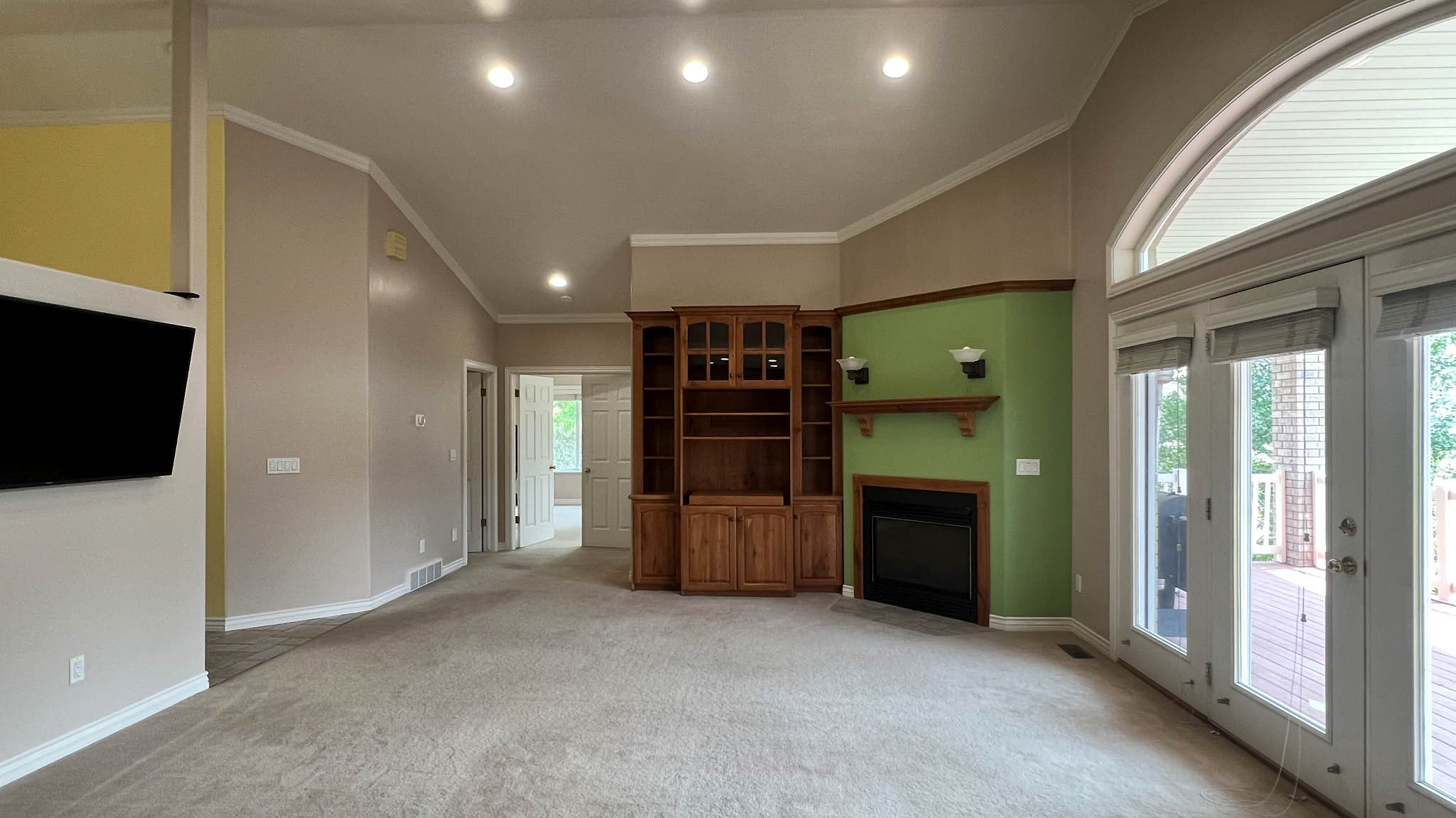 Living area featuring a built-in fireplace with a wooden mantel, integrated wood cabinetry, vaulted ceilings, and recessed lighting