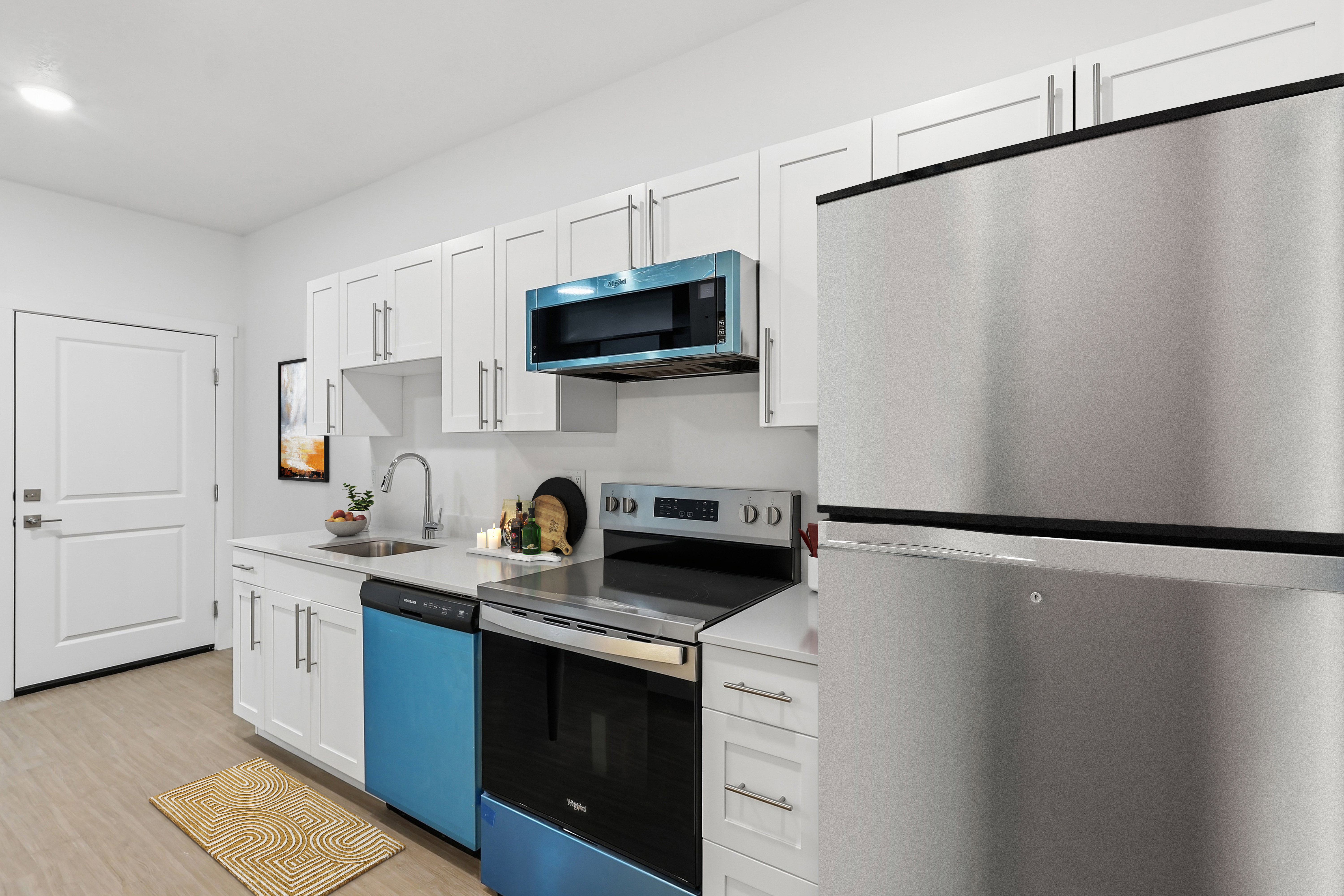 Kitchen featuring white shaker-style cabinetry, a stainless steel refrigerator, a blue dishwasher, and a blue over-the-range microwave