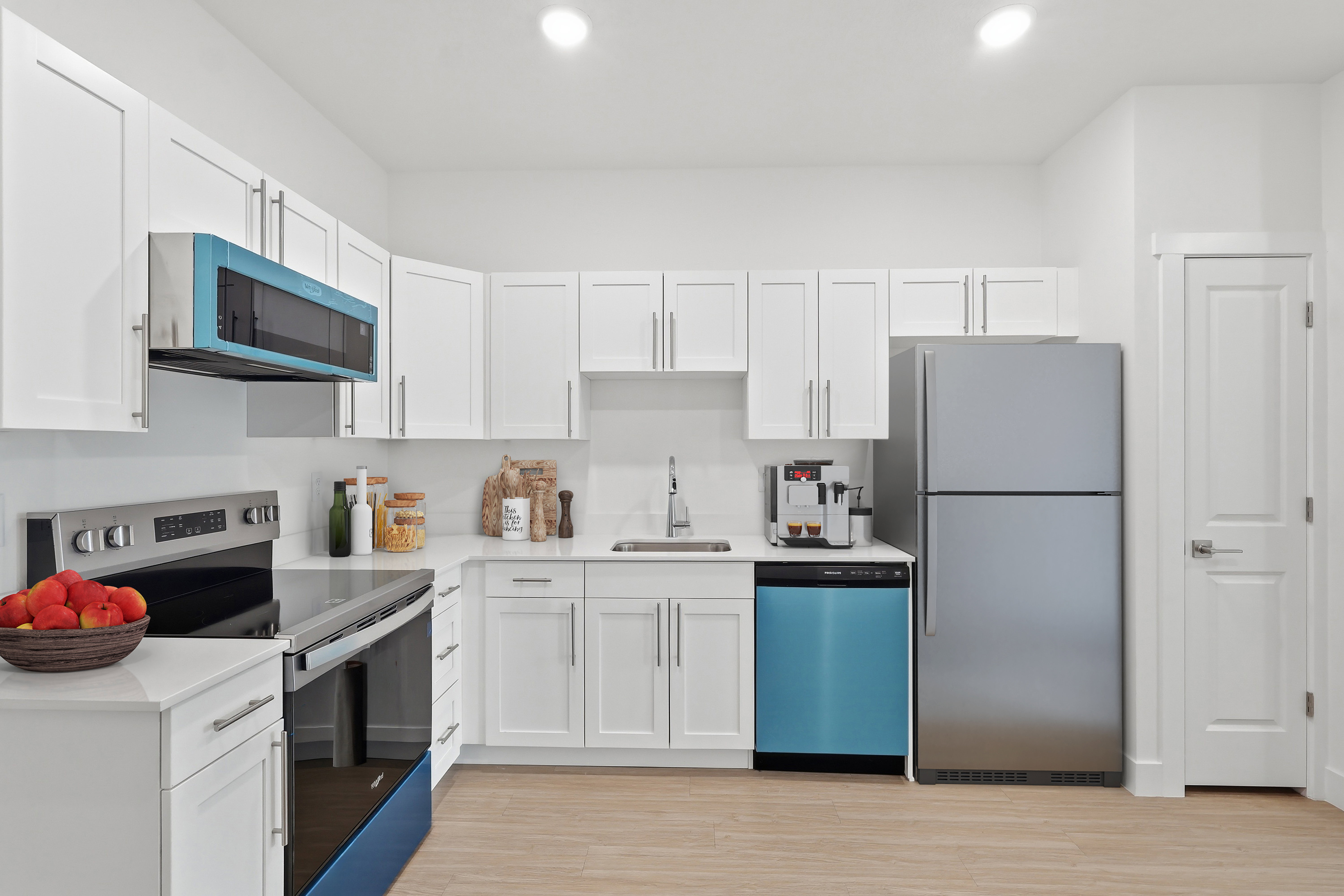 Well-appointed kitchen featuring white cabinetry, light countertops, and wood-finish flooring