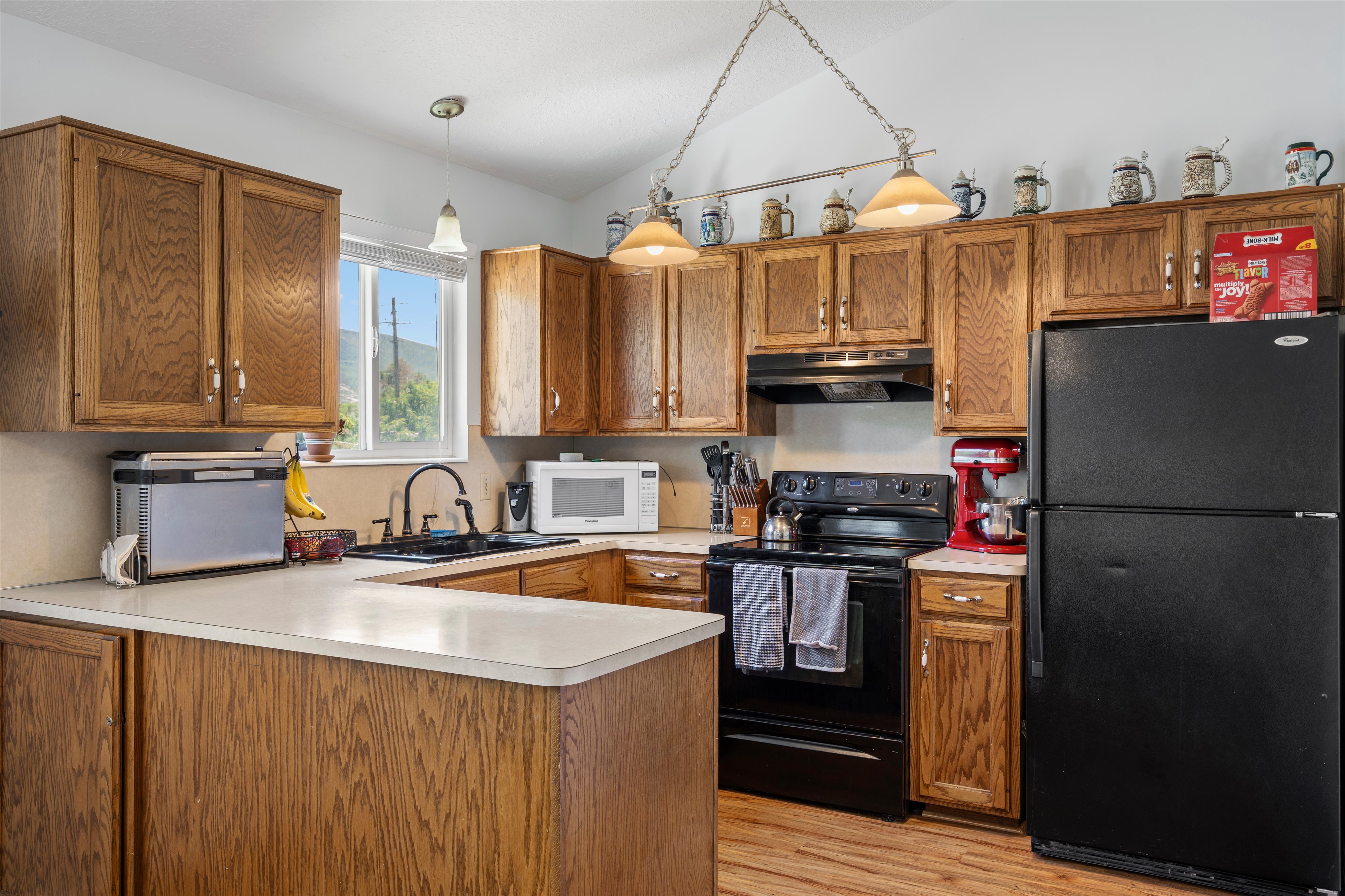 Kitchen featuring wood cabinetry, light-toned countertops, and a black appliance suite