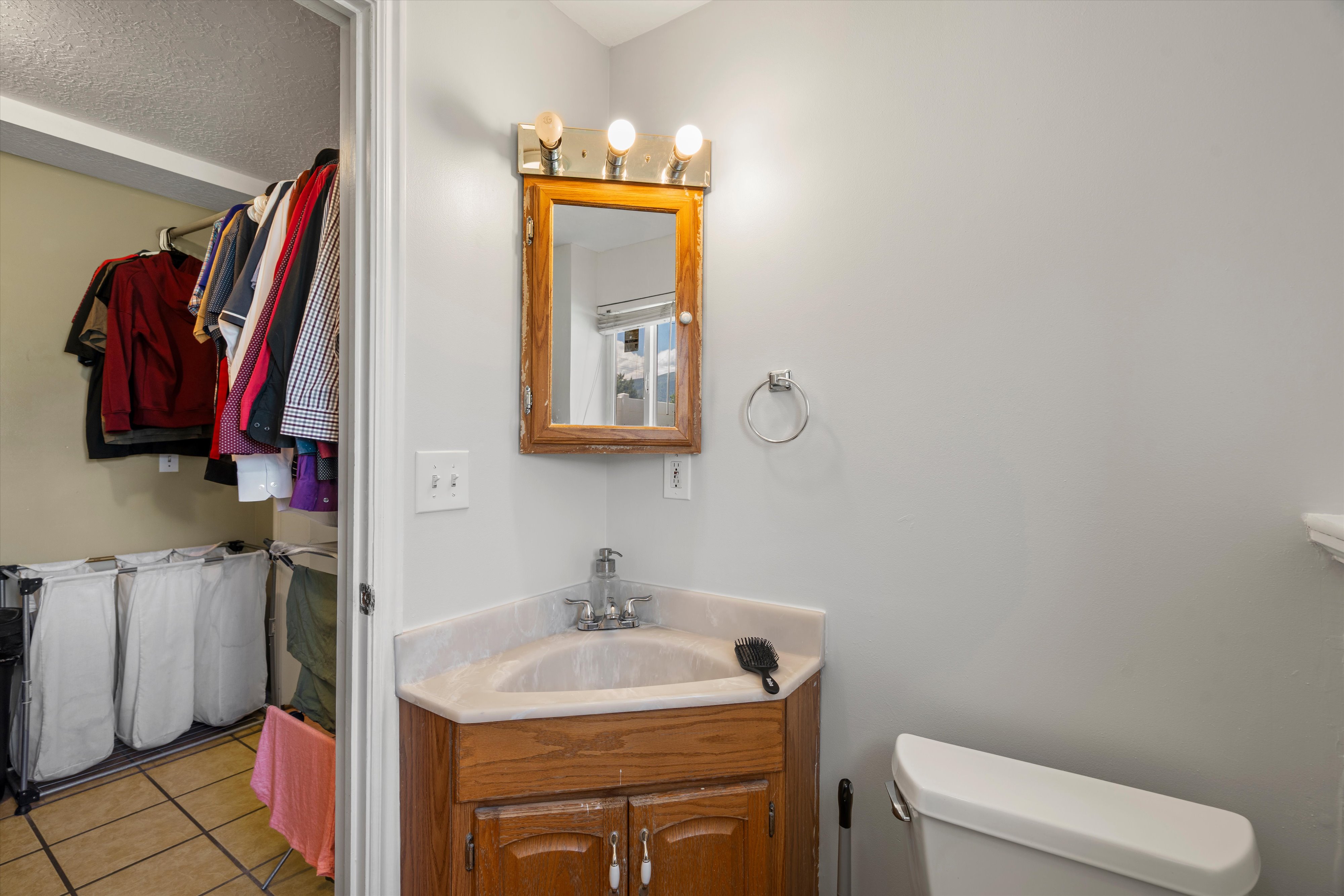 Bathroom featuring a corner vanity with a built-in sink, wood-finish cabinetry, and an overhead light fixture