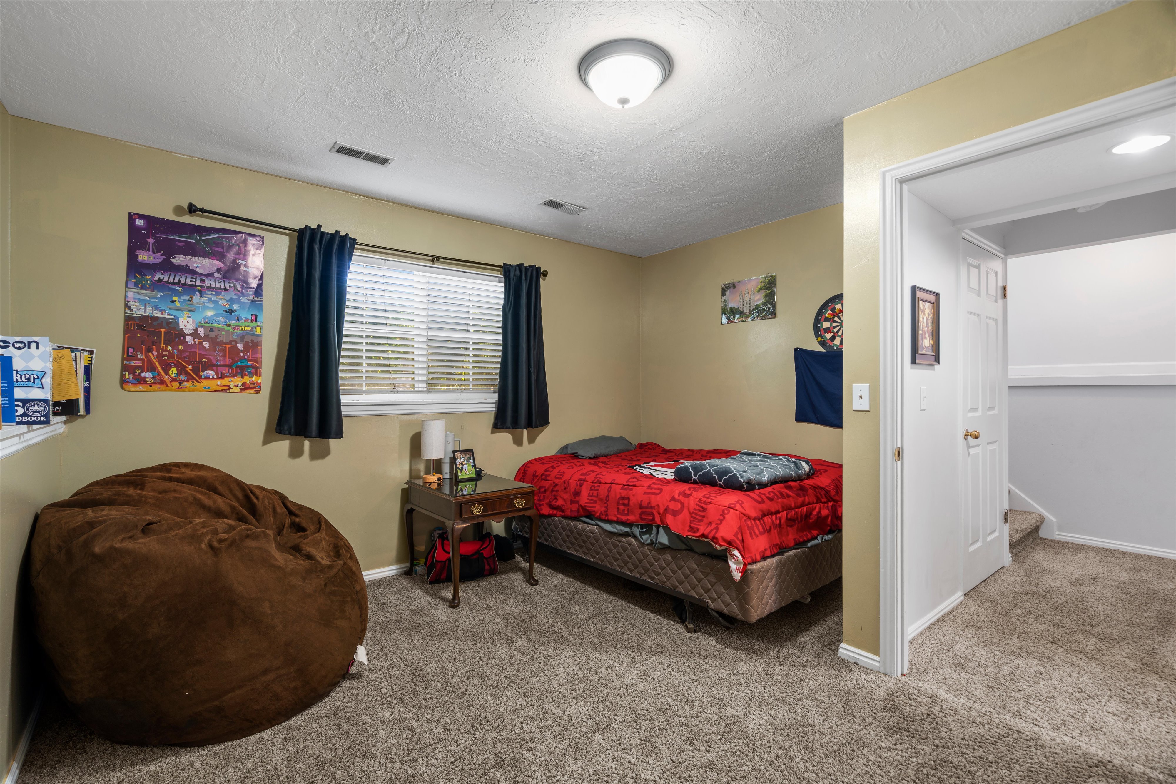 Carpeted room with a window featuring blinds and dark drapes