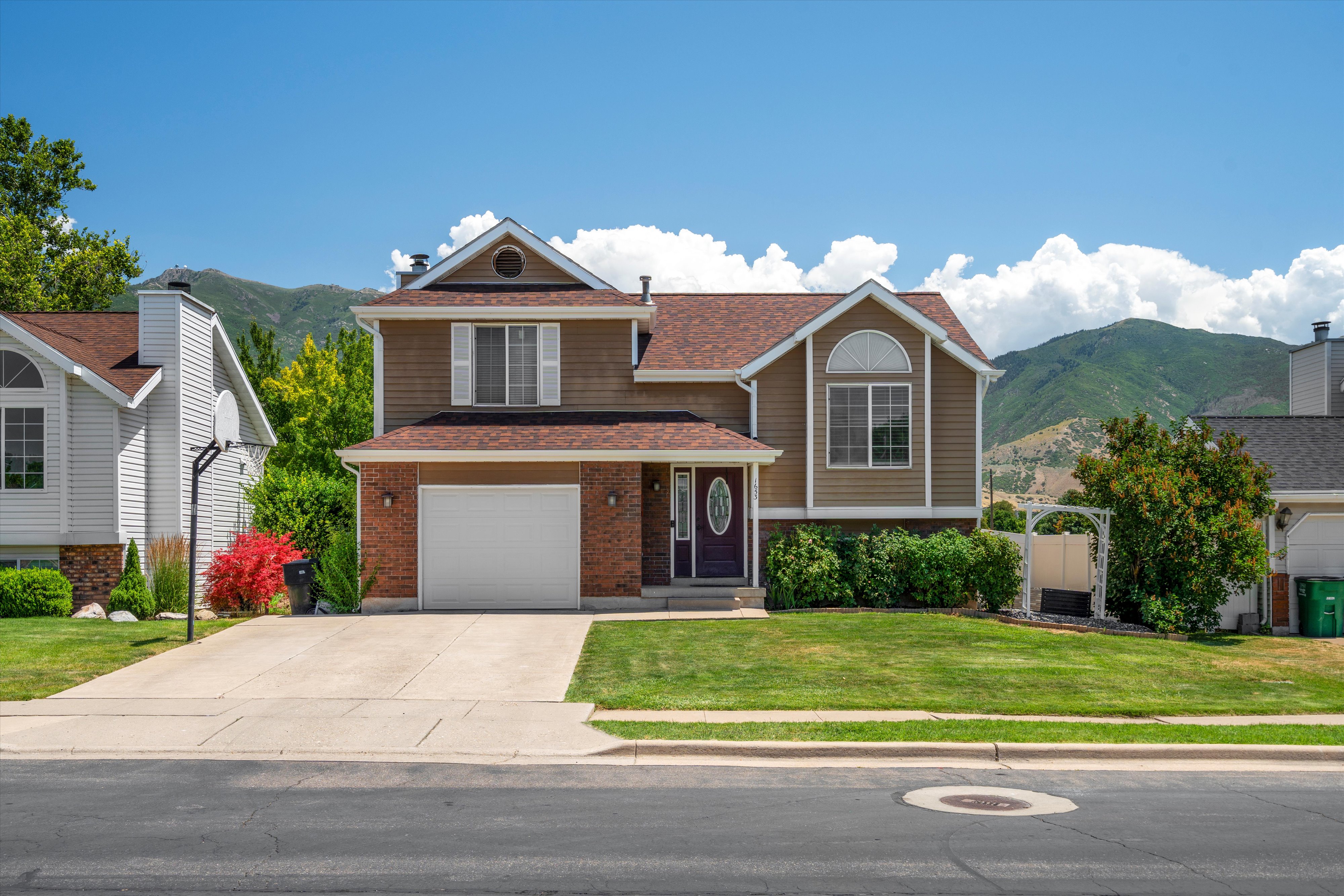 Two-story residence featuring a brown shingle roof, brick facade accents, and a single-car garage