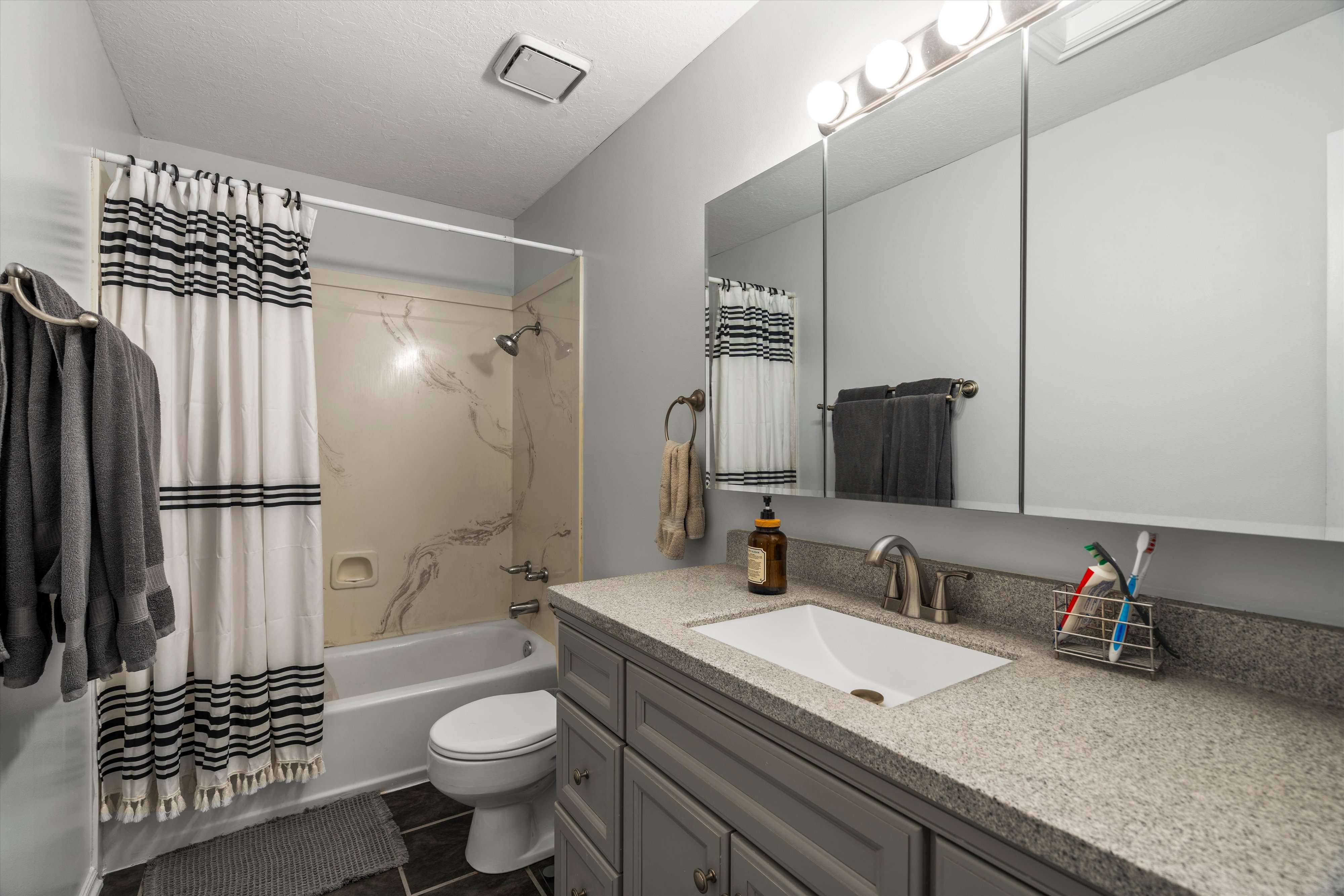 Bathroom vanity featuring a light gray countertop, undermount sink, and brushed nickel faucet