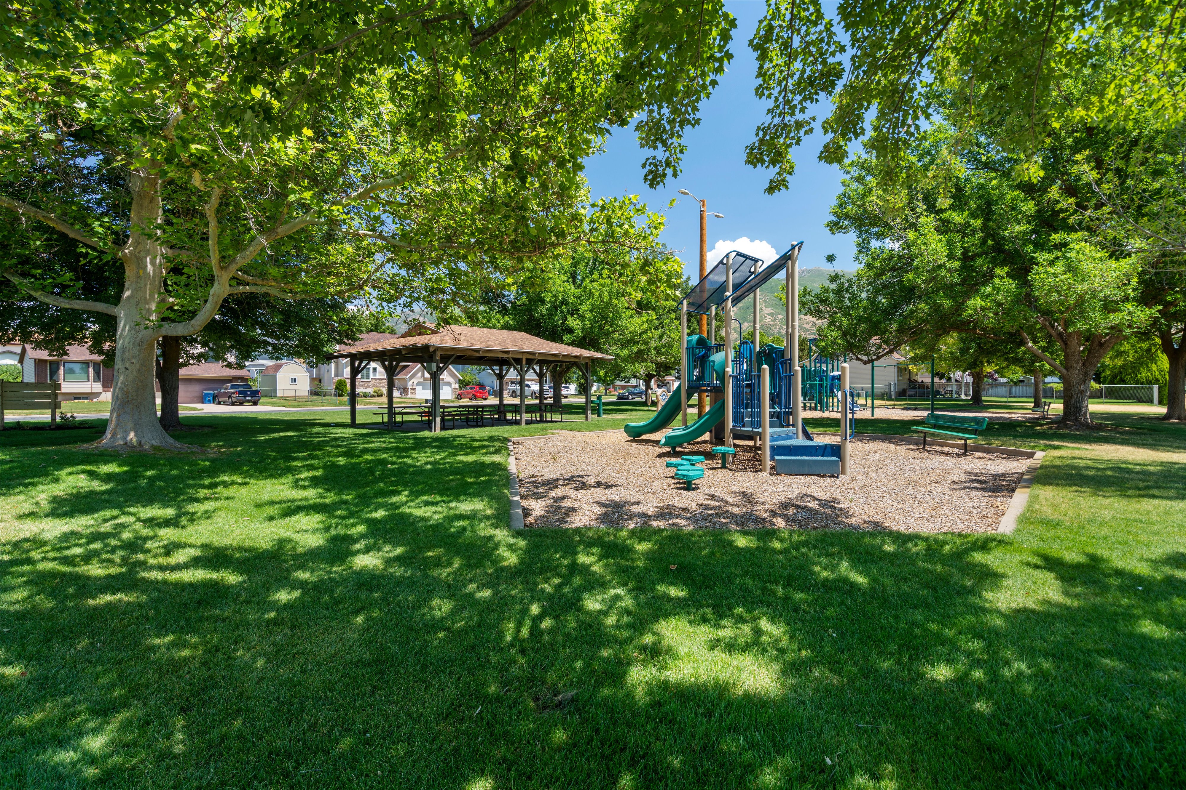 Expansive green space featuring a shaded playground with multiple slides and climbing structures