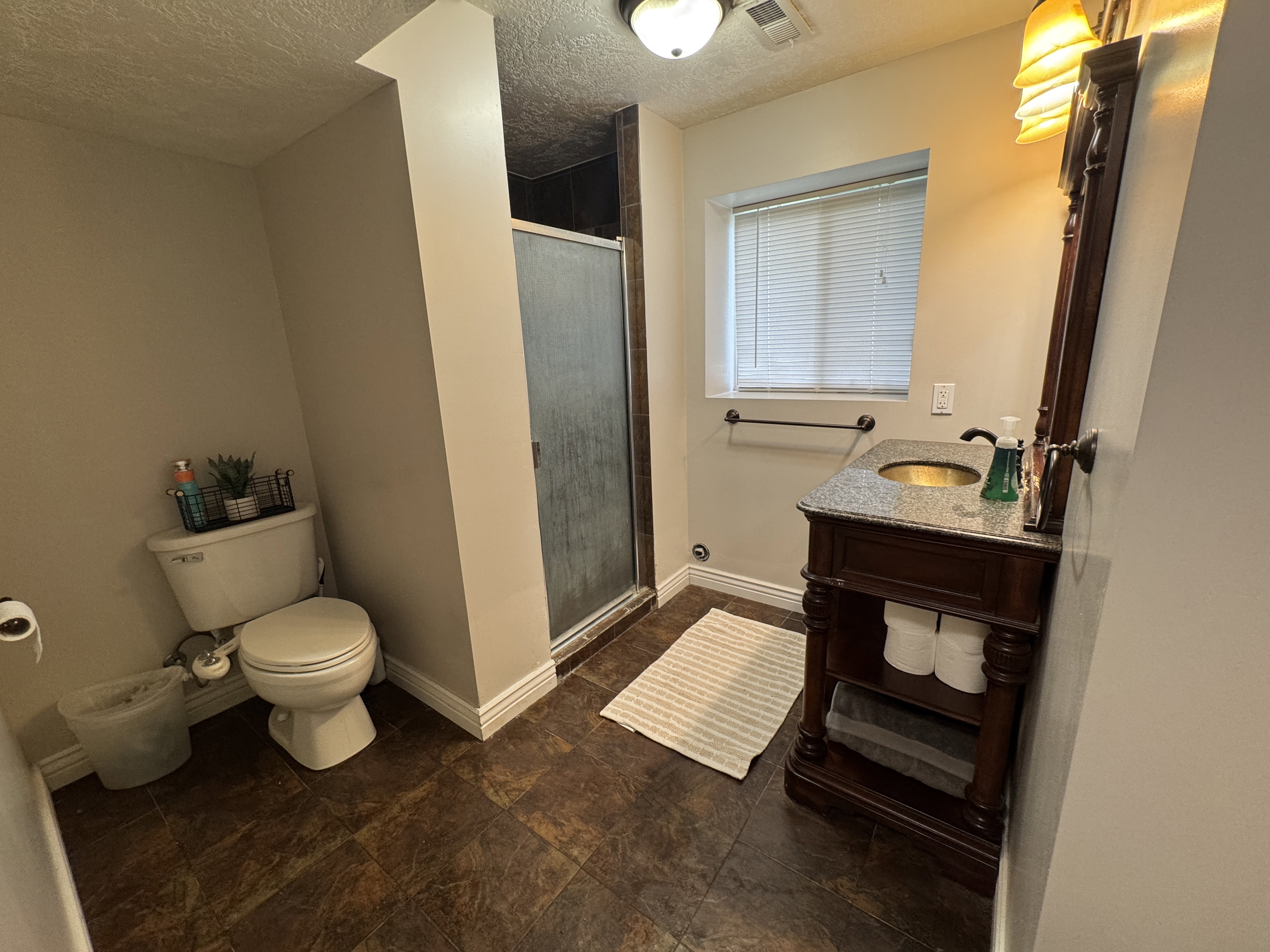 Bathroom featuring a dark wood-finish vanity with an undermount sink, granite-style countertop, and ornate mirror
