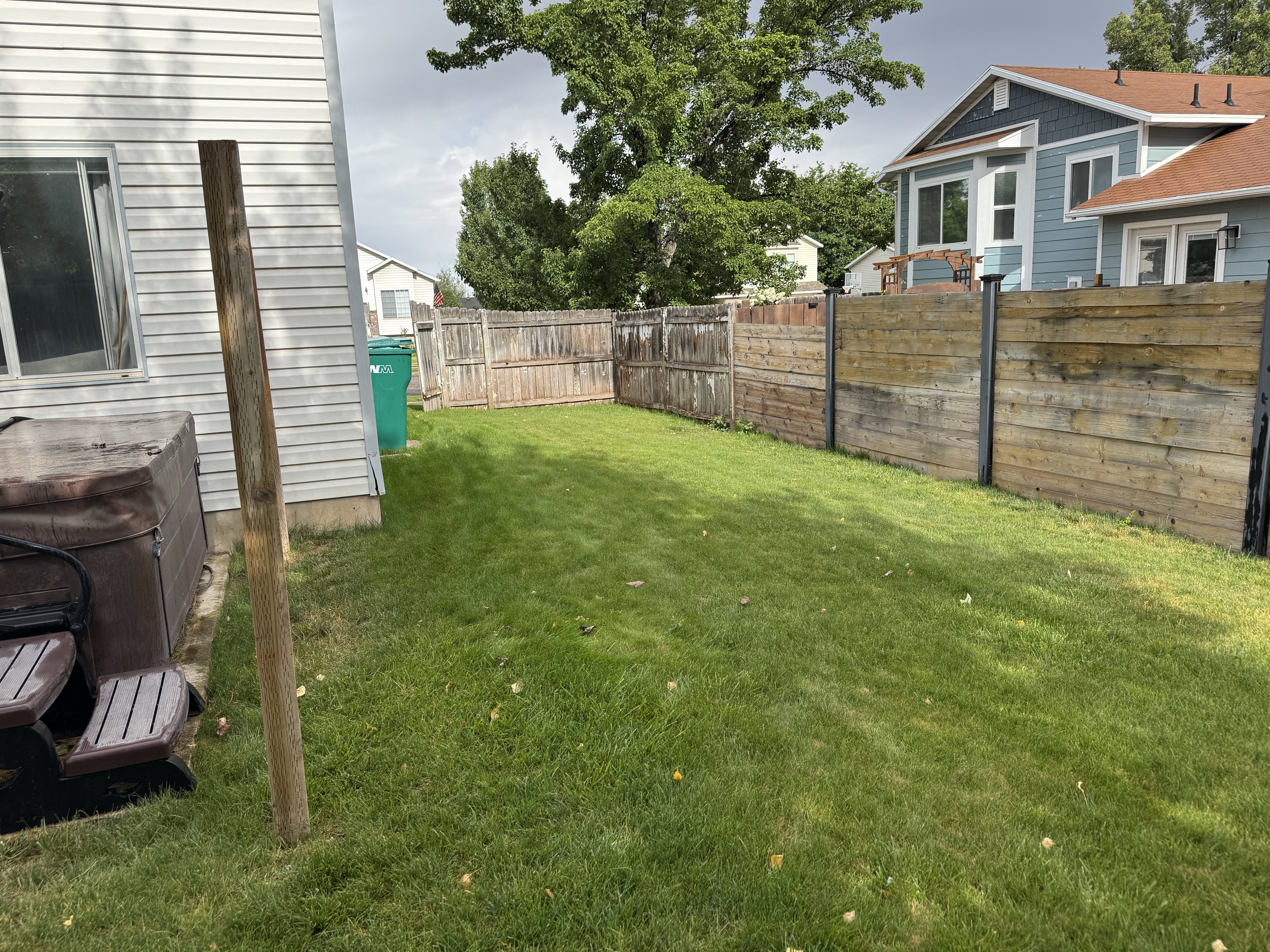 Expansive green lawn with a perimeter fence featuring horizontal wood paneling and vertical wood planks