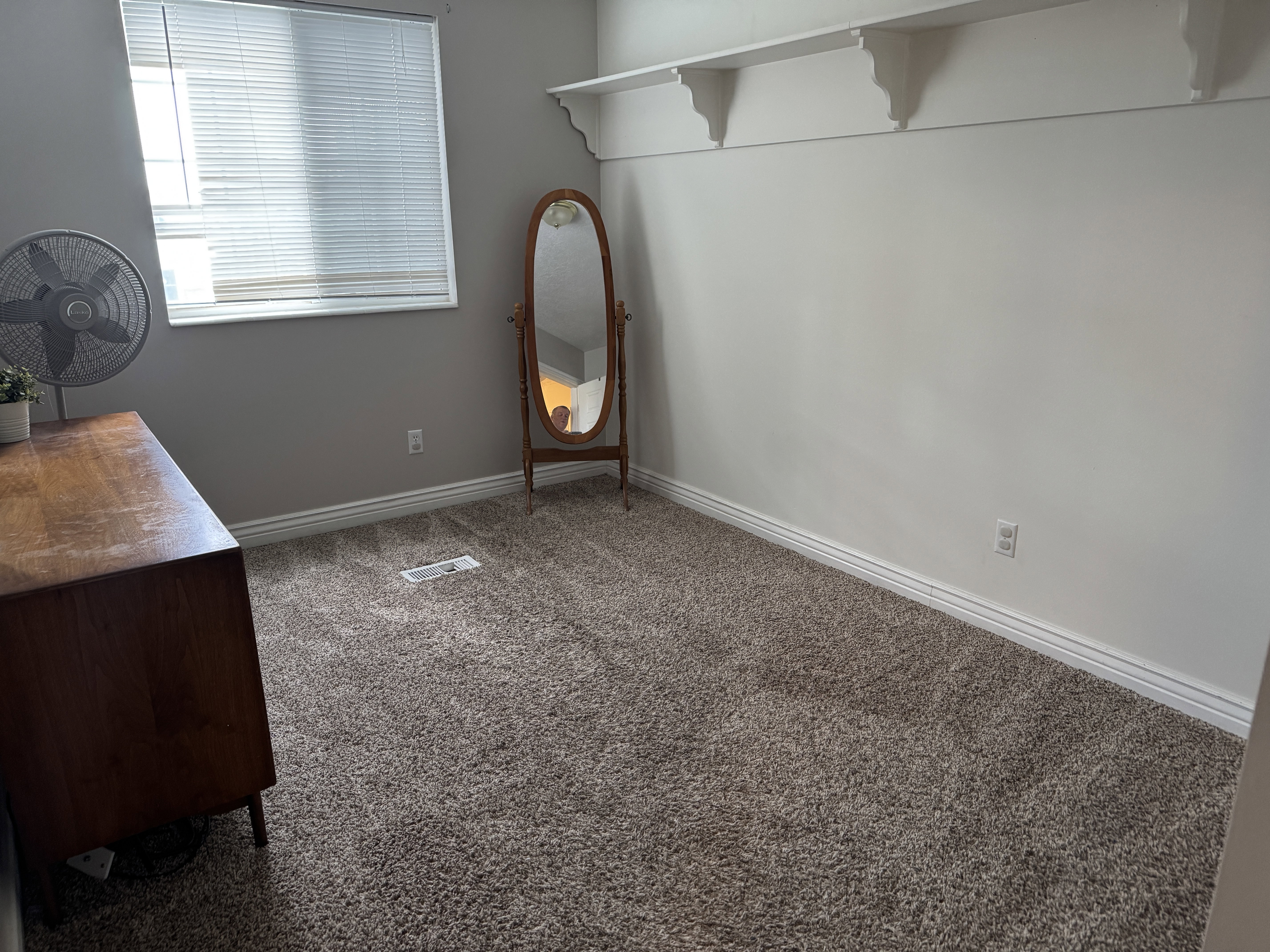 Carpeted room with a window featuring horizontal blinds