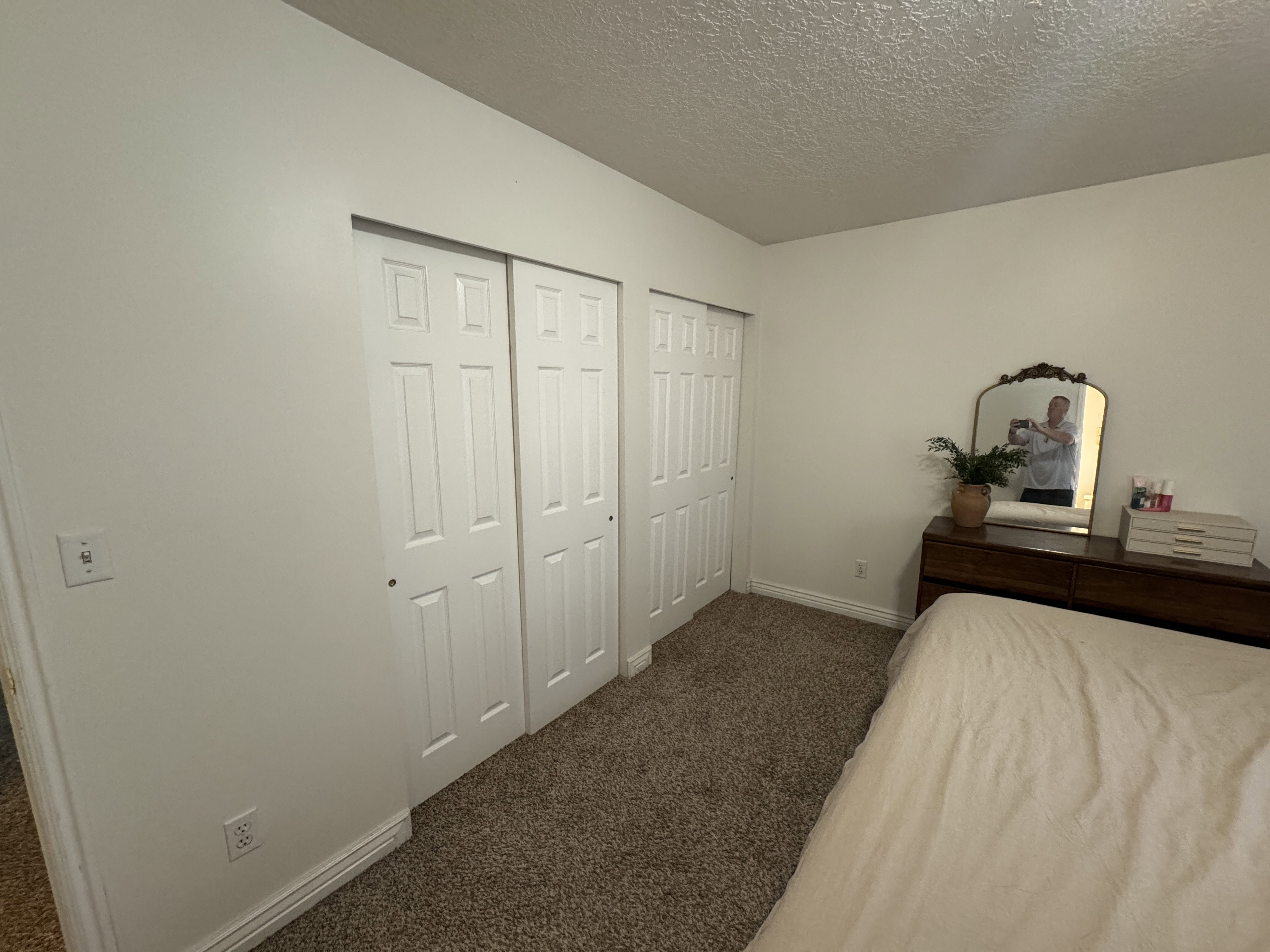 White sliding closet doors with six-panel design, textured ceiling, and neutral-toned wall paint