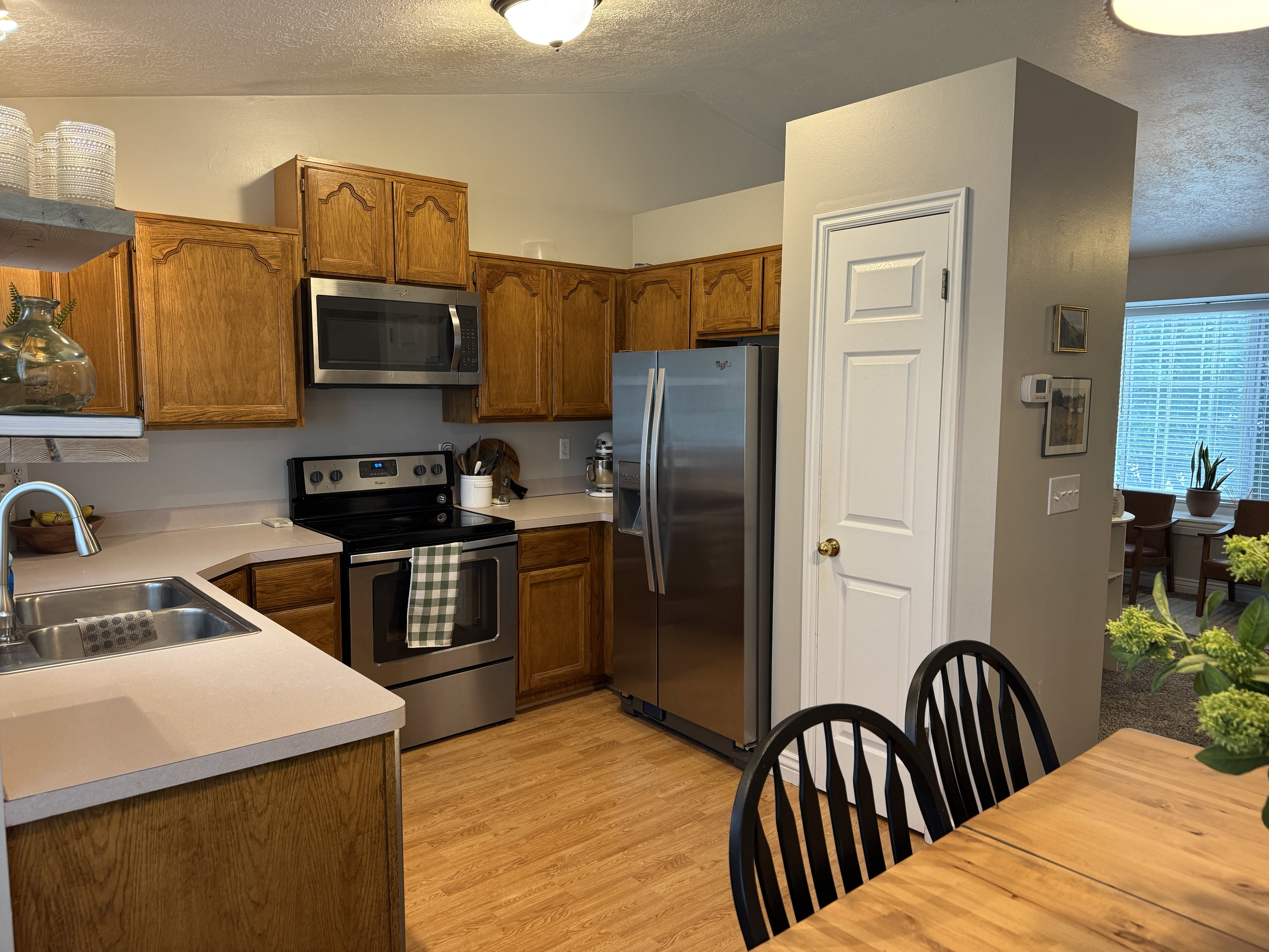 Kitchen featuring wood-finish cabinetry, stainless steel appliances, a double basin sink, light-toned countertops, and wood-finish flooring