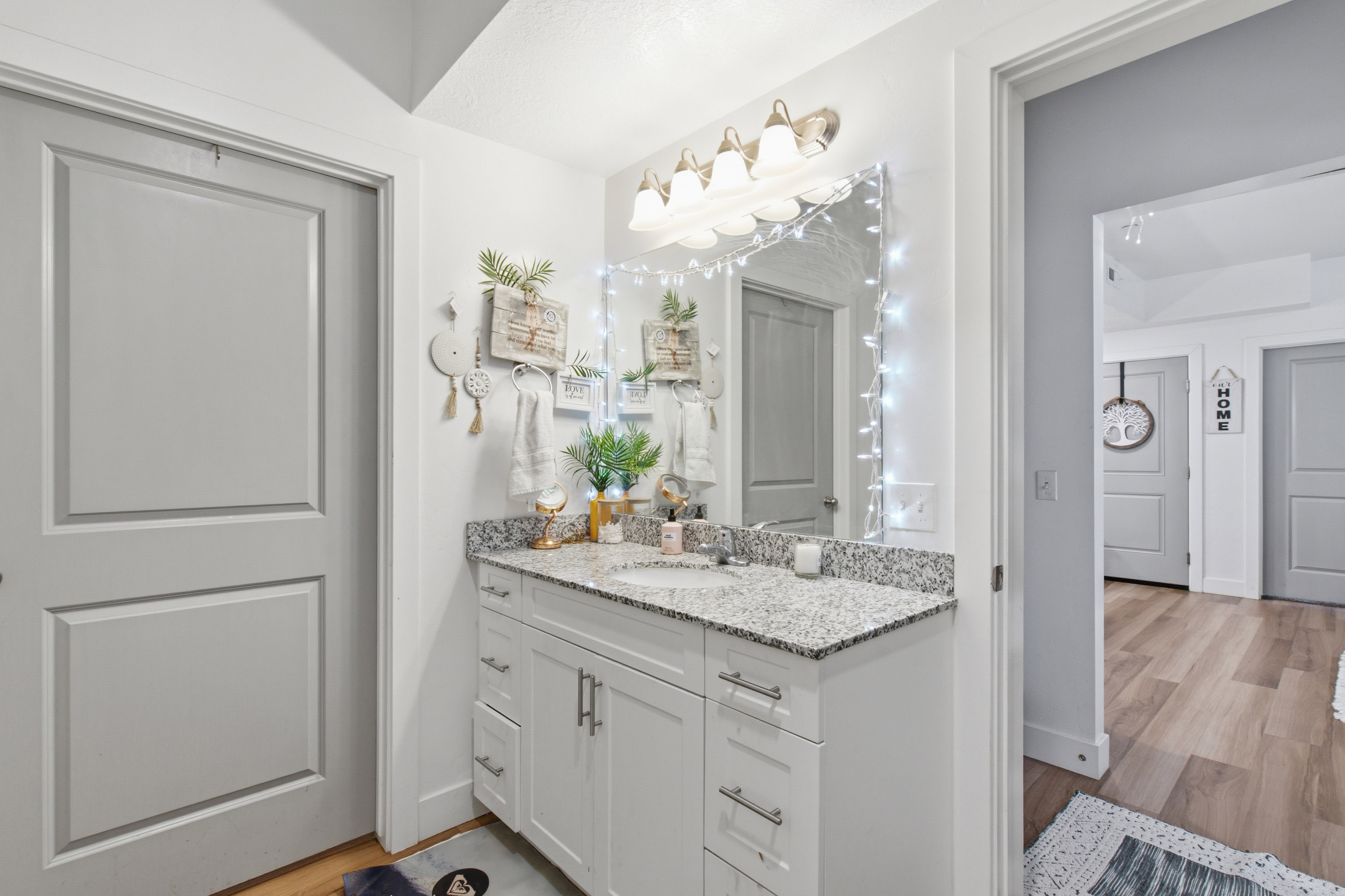 Bathroom vanity featuring a light-colored countertop, undermount sink, and white cabinetry with brushed nickel hardware