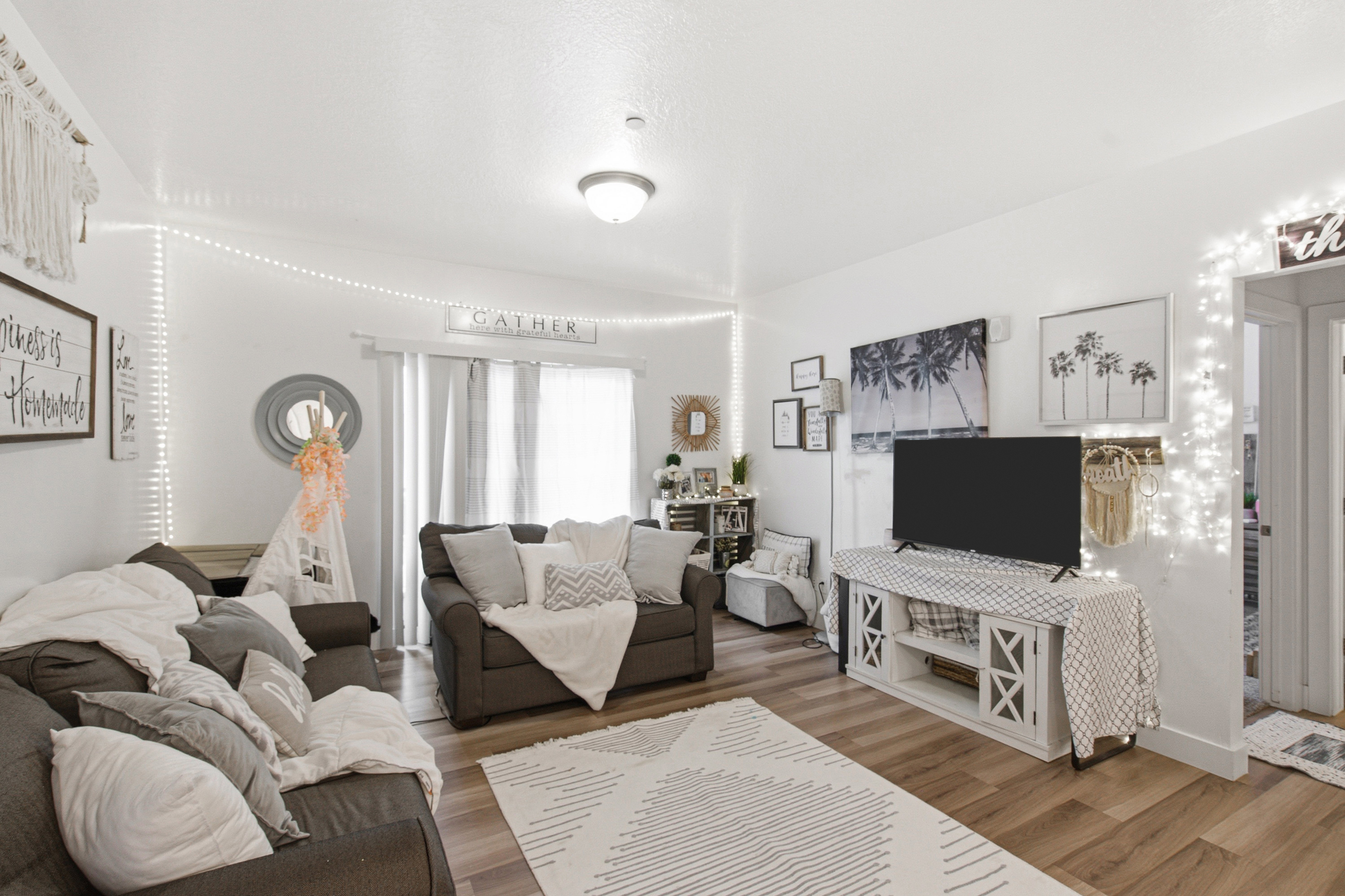 Spacious living area featuring light wood-finish flooring, white walls, and a ceiling-mounted light fixture