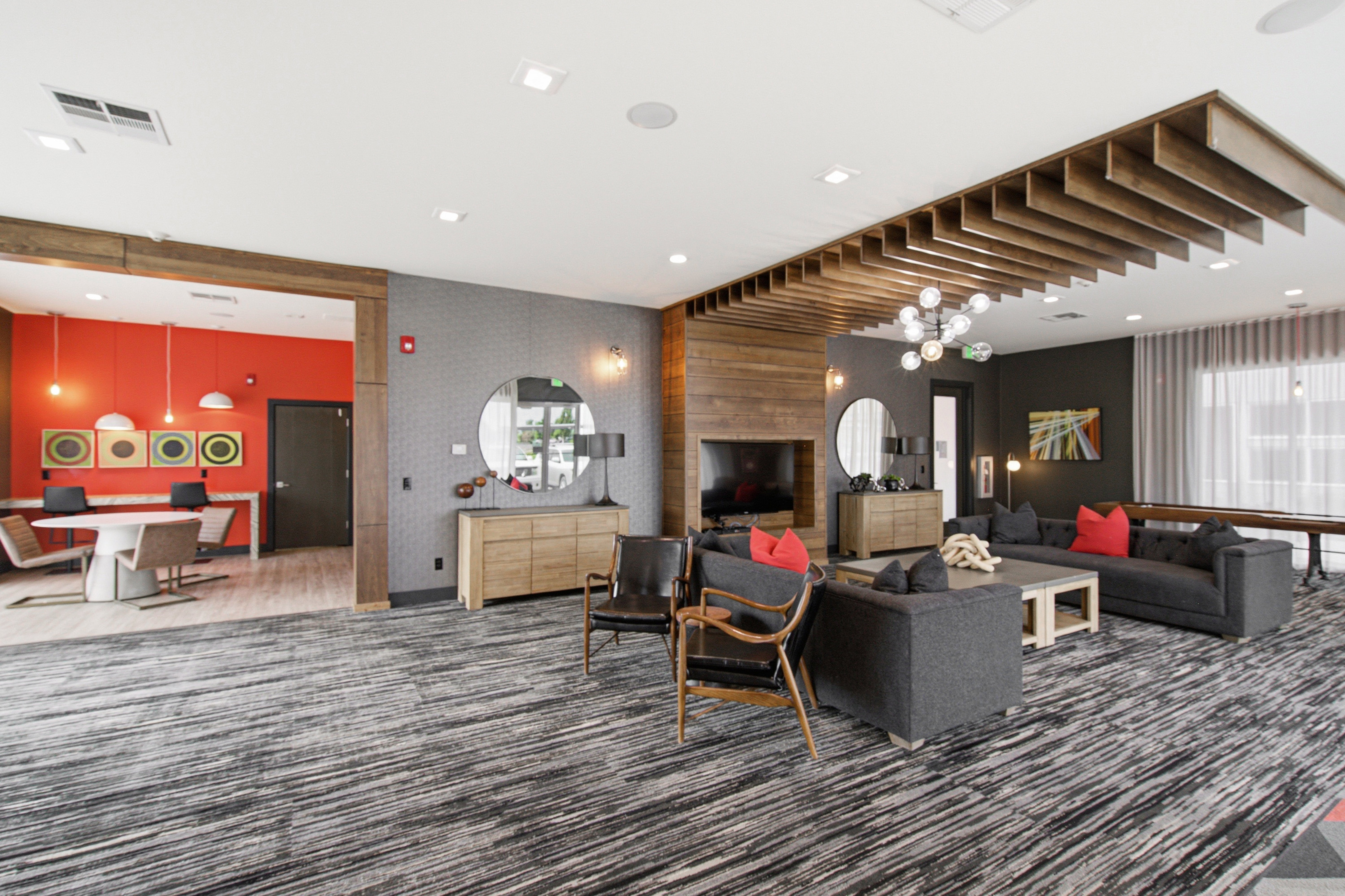 Spacious lounge area featuring a wood slat ceiling, wood panel accent wall, and recessed lighting