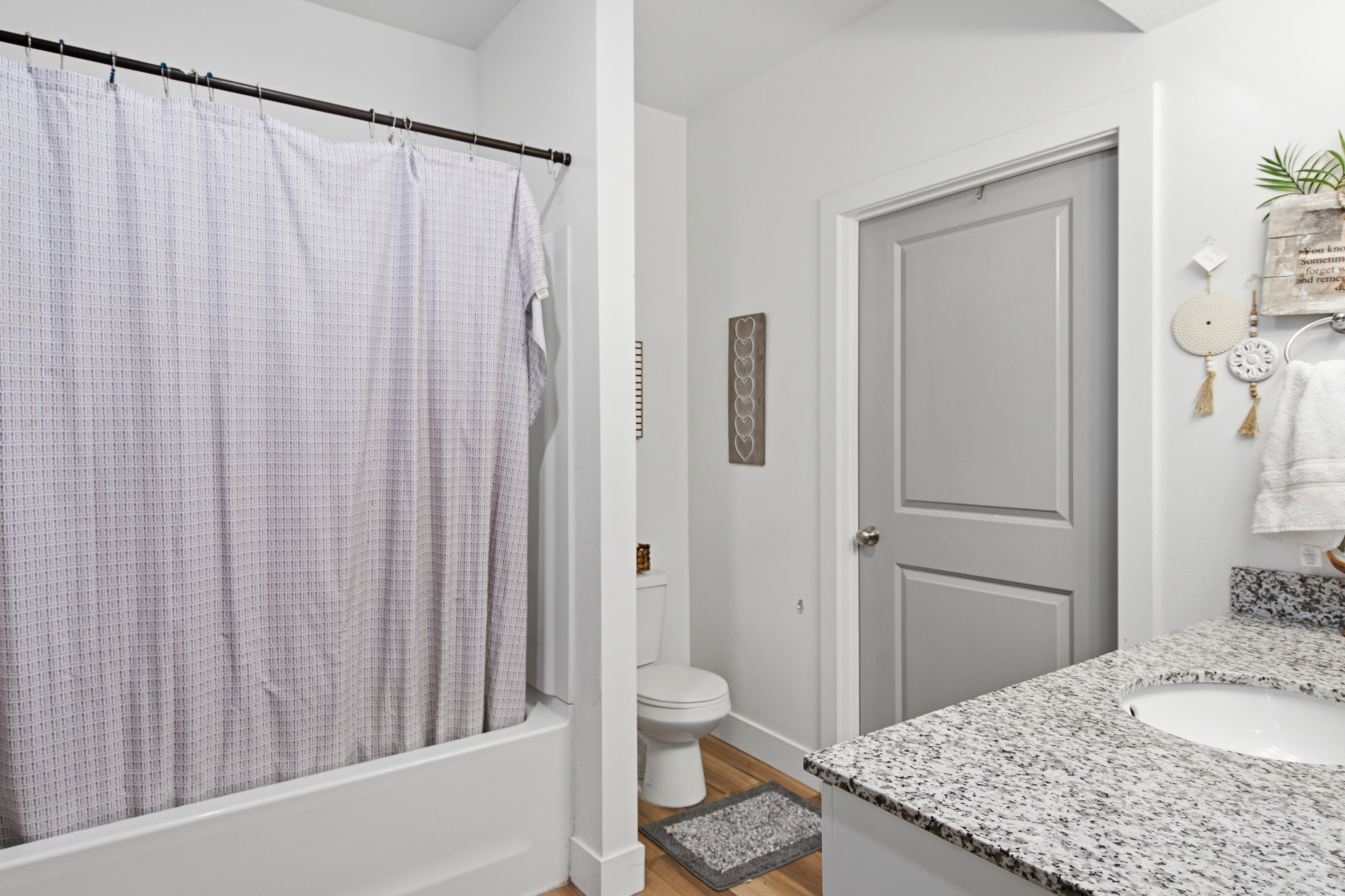 Bathroom featuring a built-in tub with shower, a vanity with a white composite sink, and a speckled countertop