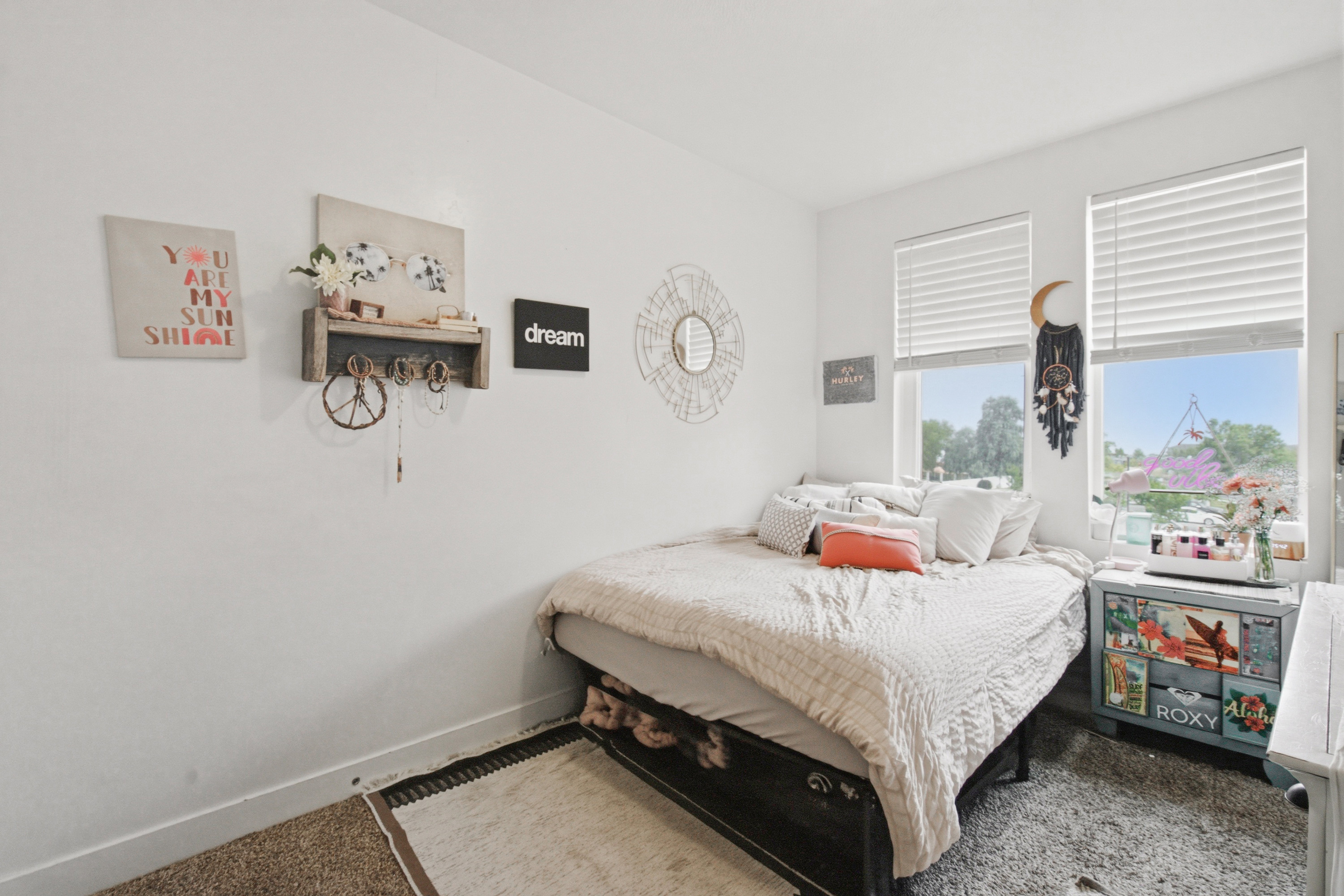 Room featuring two large windows with blinds, light-toned walls, and carpet flooring