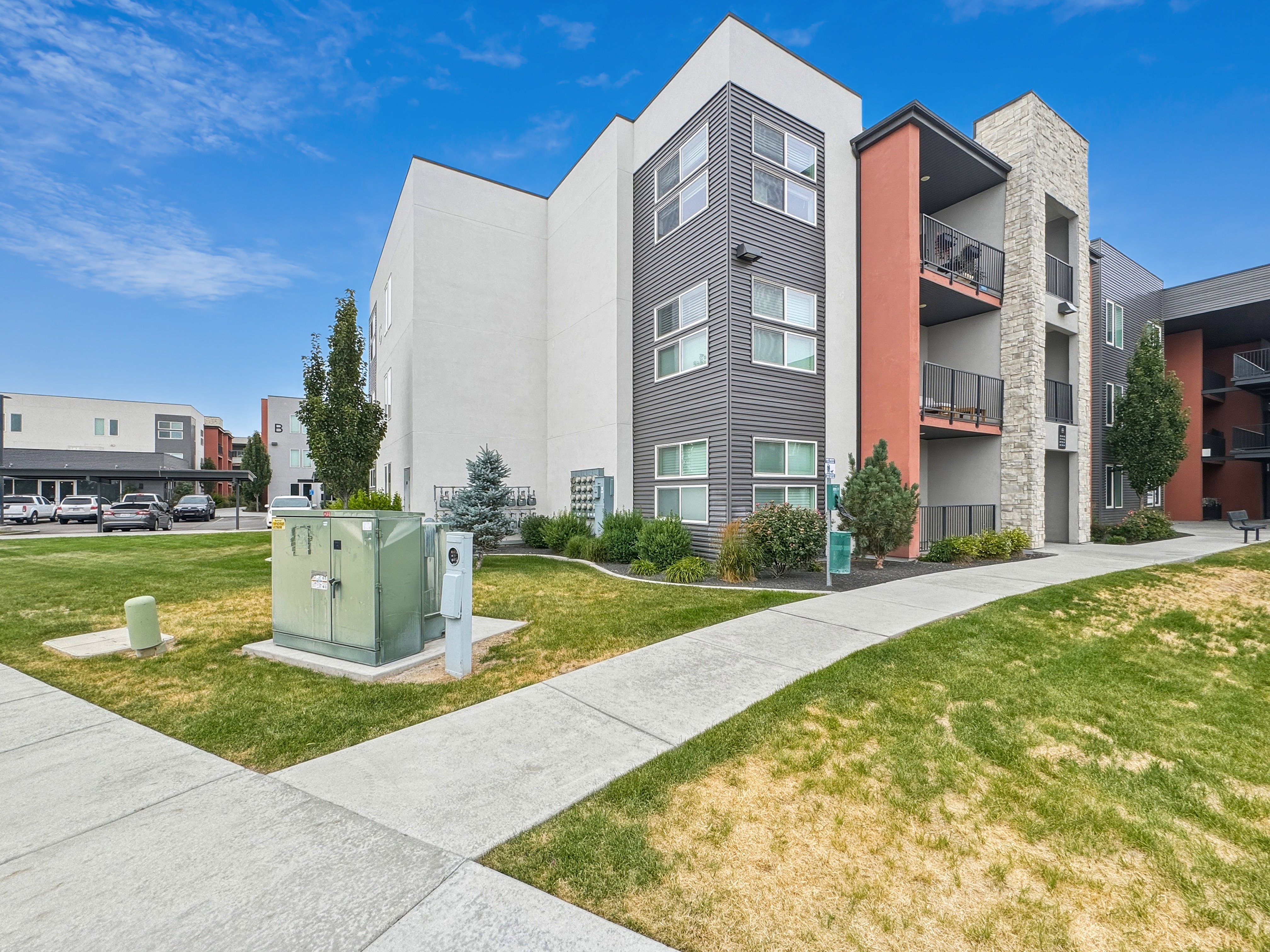 Contemporary multi-story building featuring a blend of white, gray, and earthy red exterior finishes