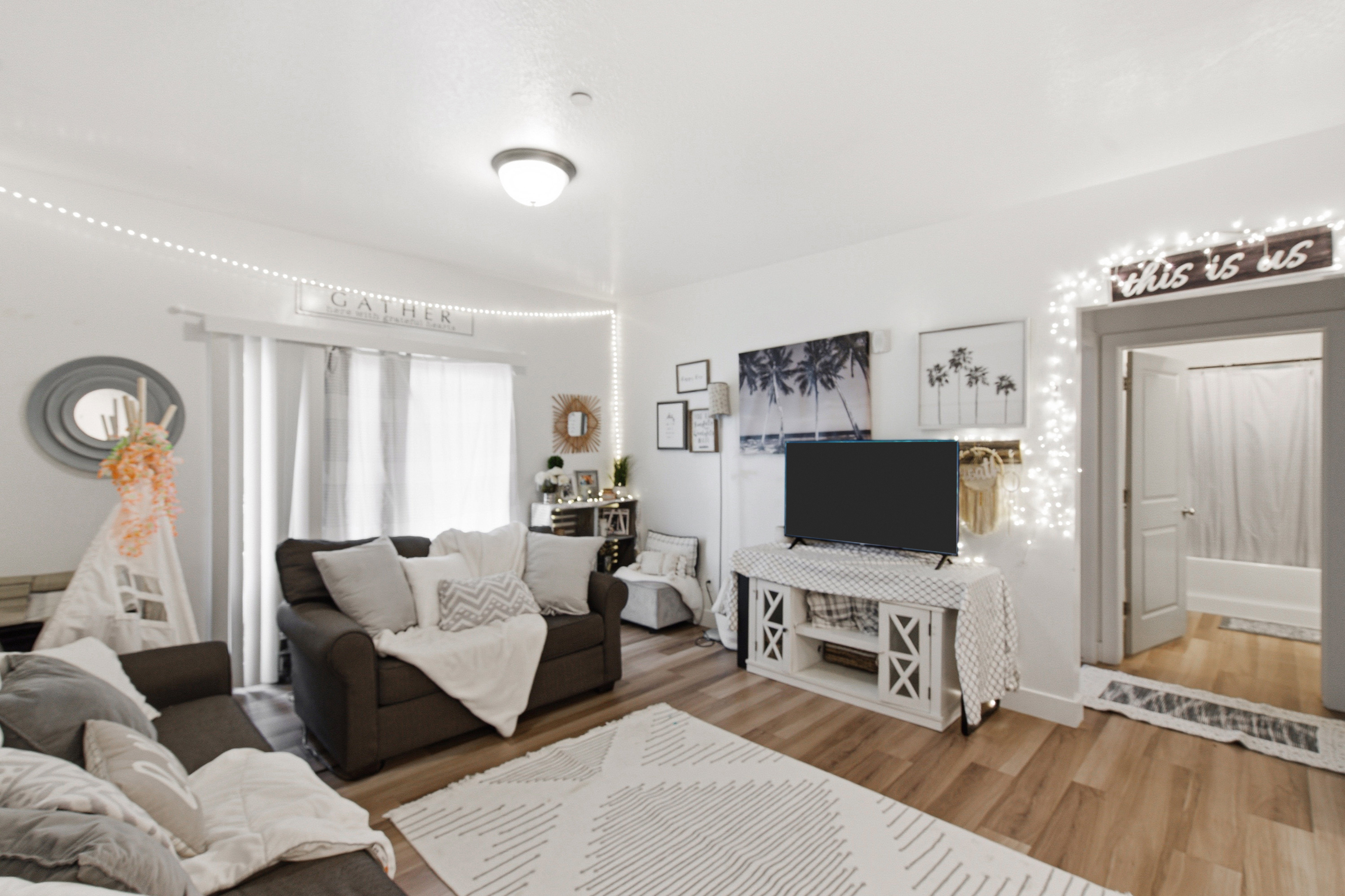 Spacious living area featuring wood-finish flooring, white walls, and a contemporary ceiling light fixture