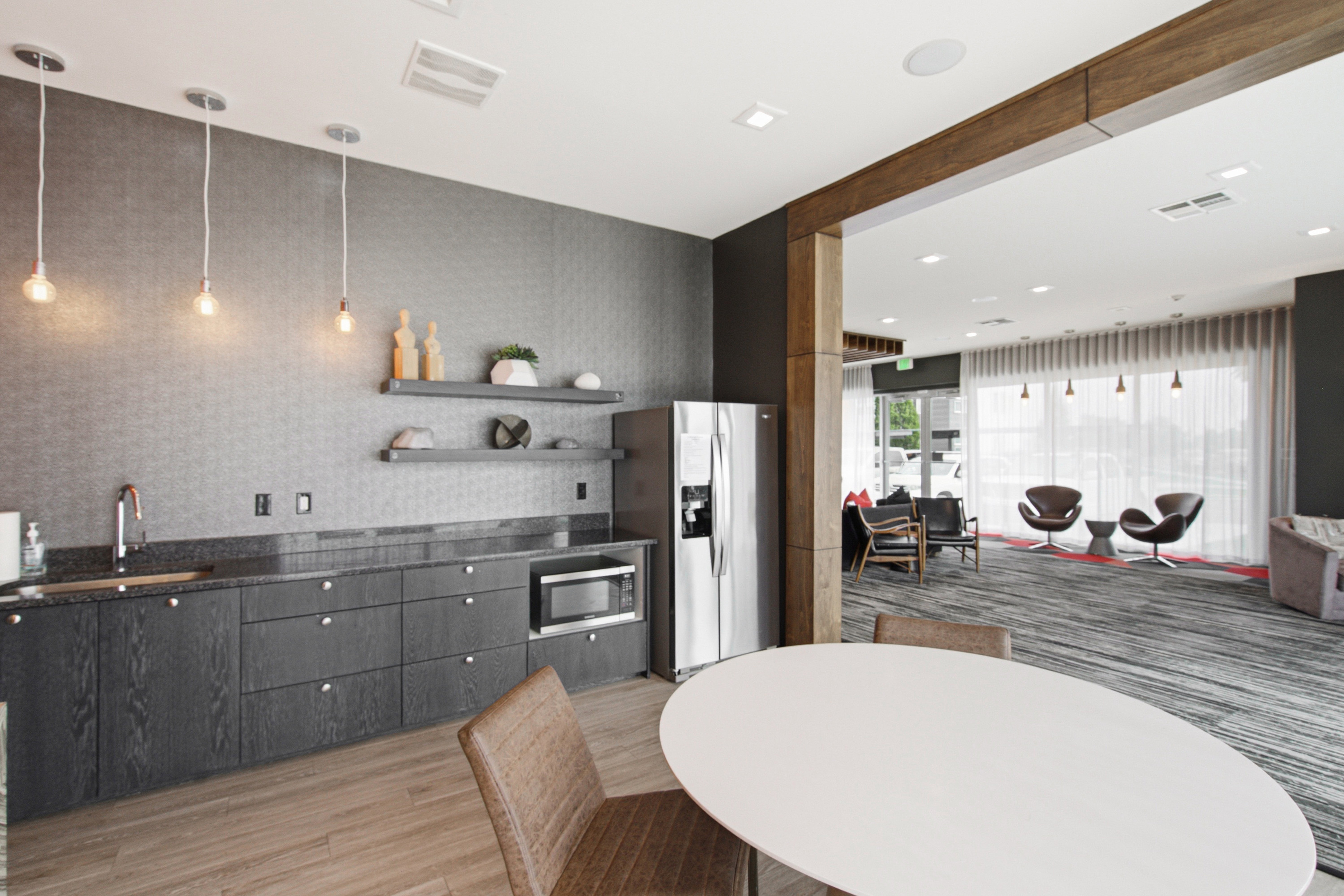 Kitchenette featuring dark wood-finish cabinetry, dark stone countertops, and a stainless steel refrigerator