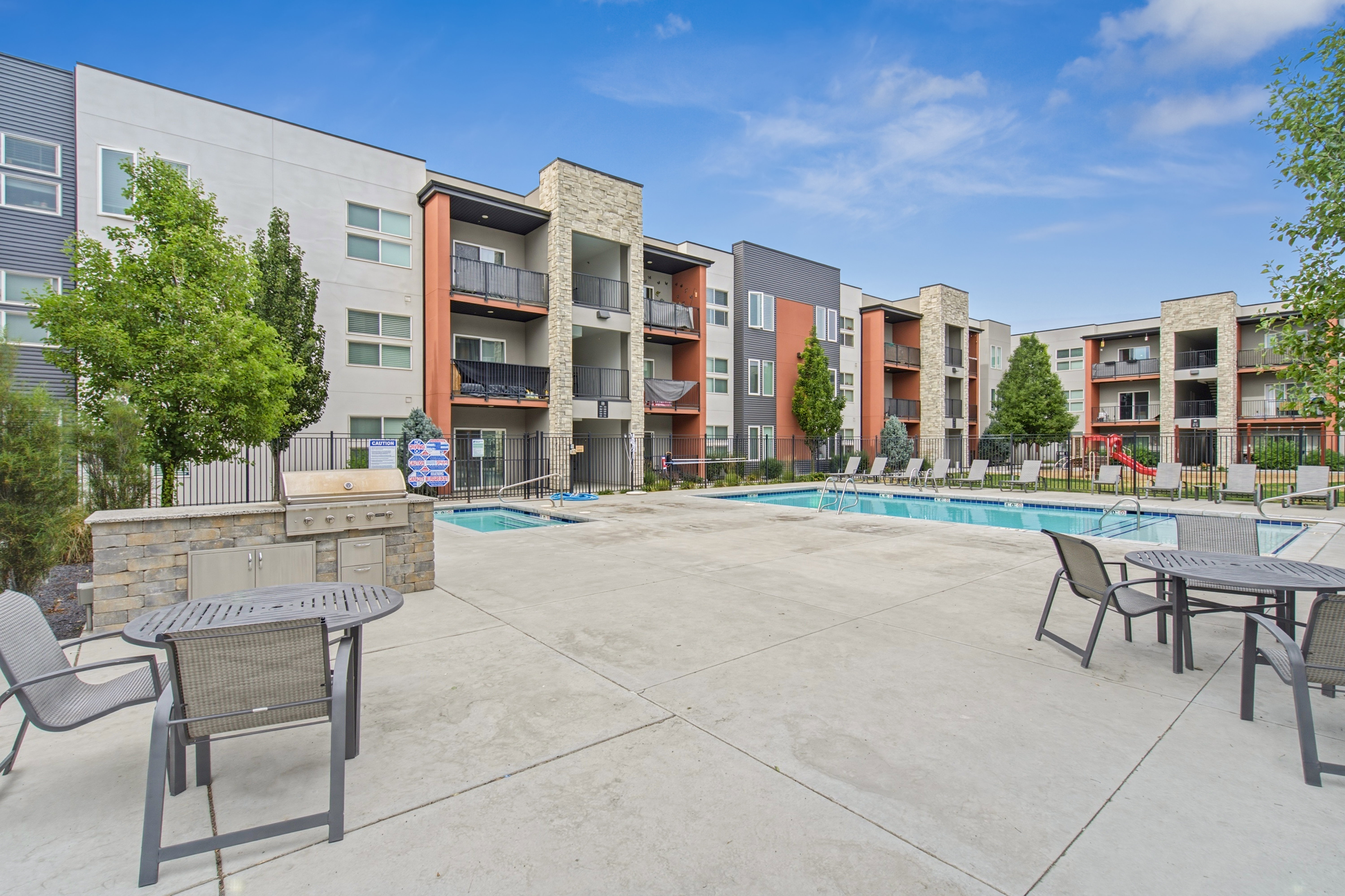 Outdoor amenity area featuring a swimming pool, separate spa, and built-in outdoor kitchen with grill