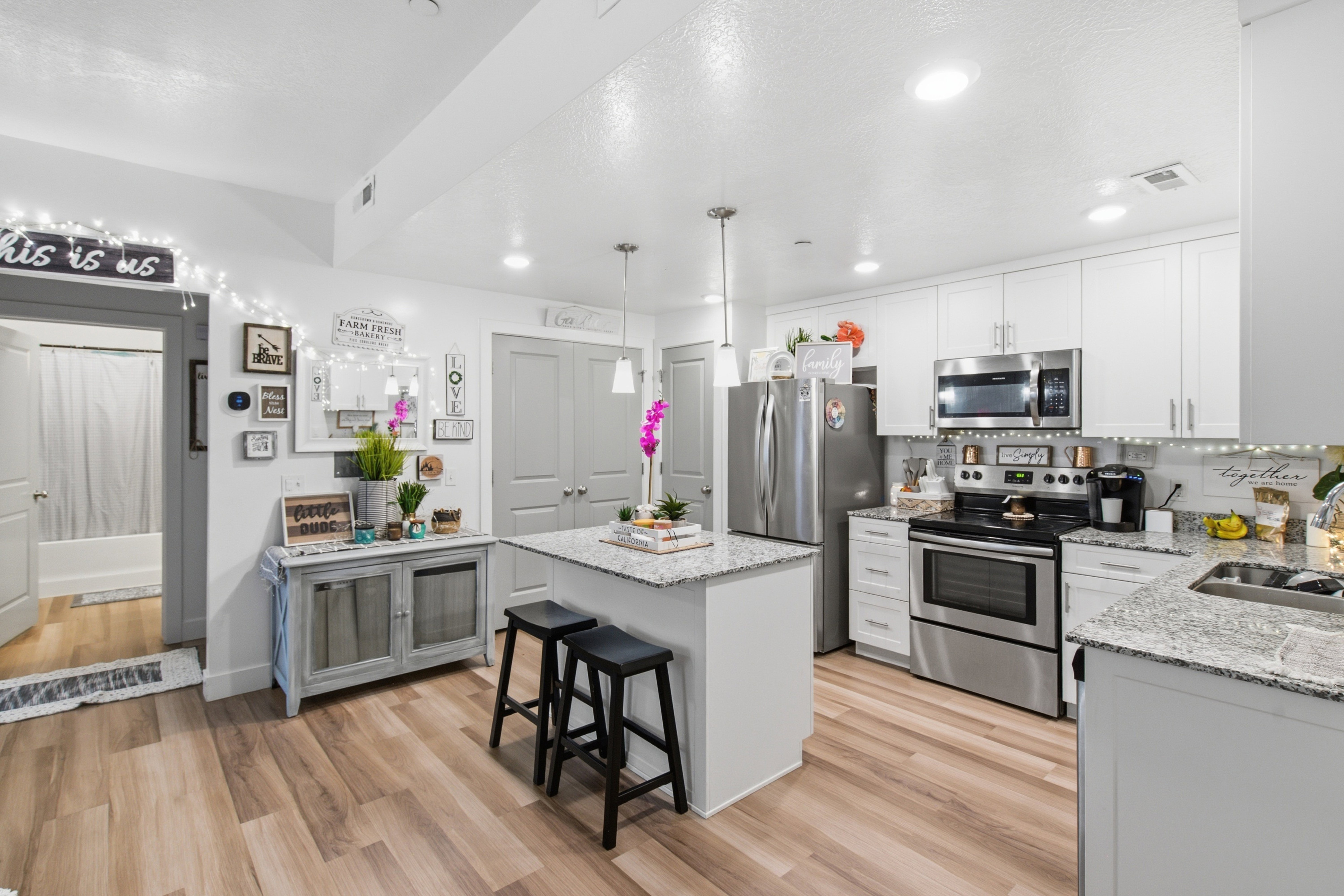 Modern kitchen featuring white cabinetry, stainless steel appliances, and wood-finish flooring