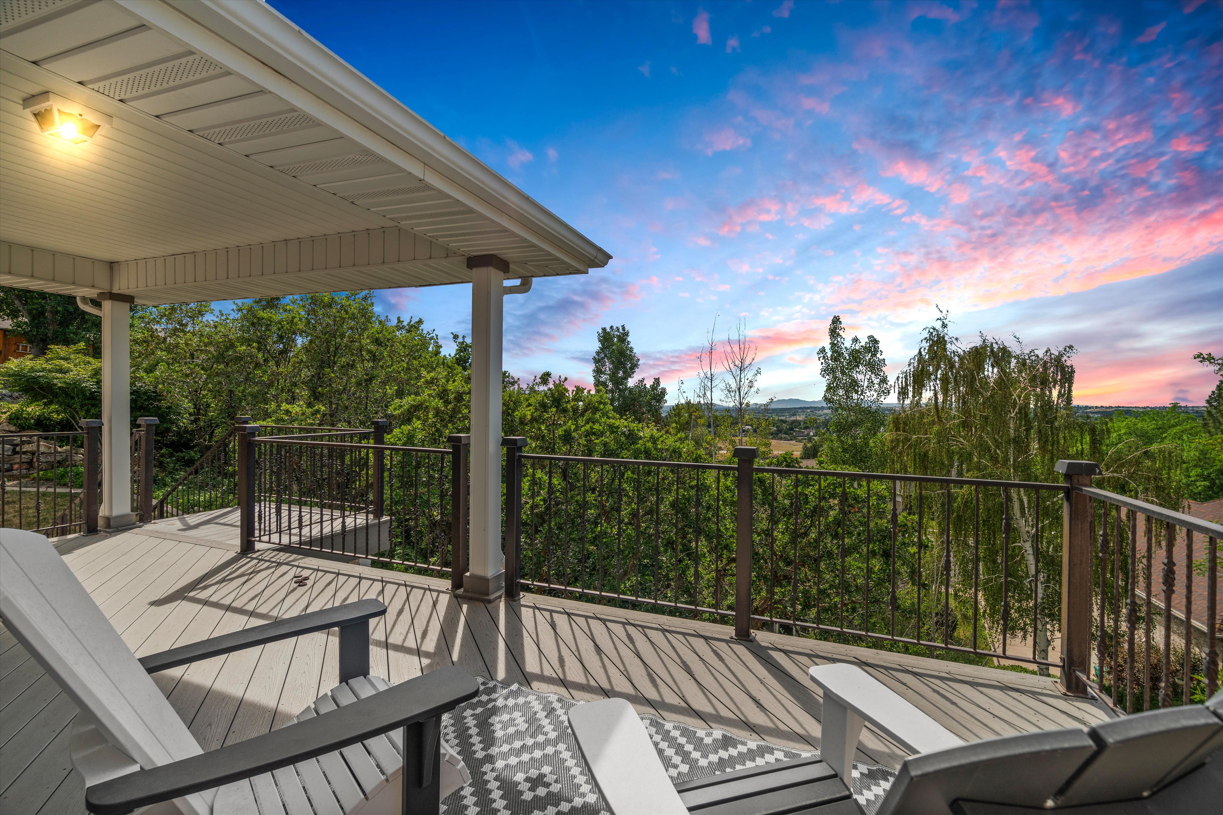 Covered outdoor deck featuring wood-finish flooring and dark railings