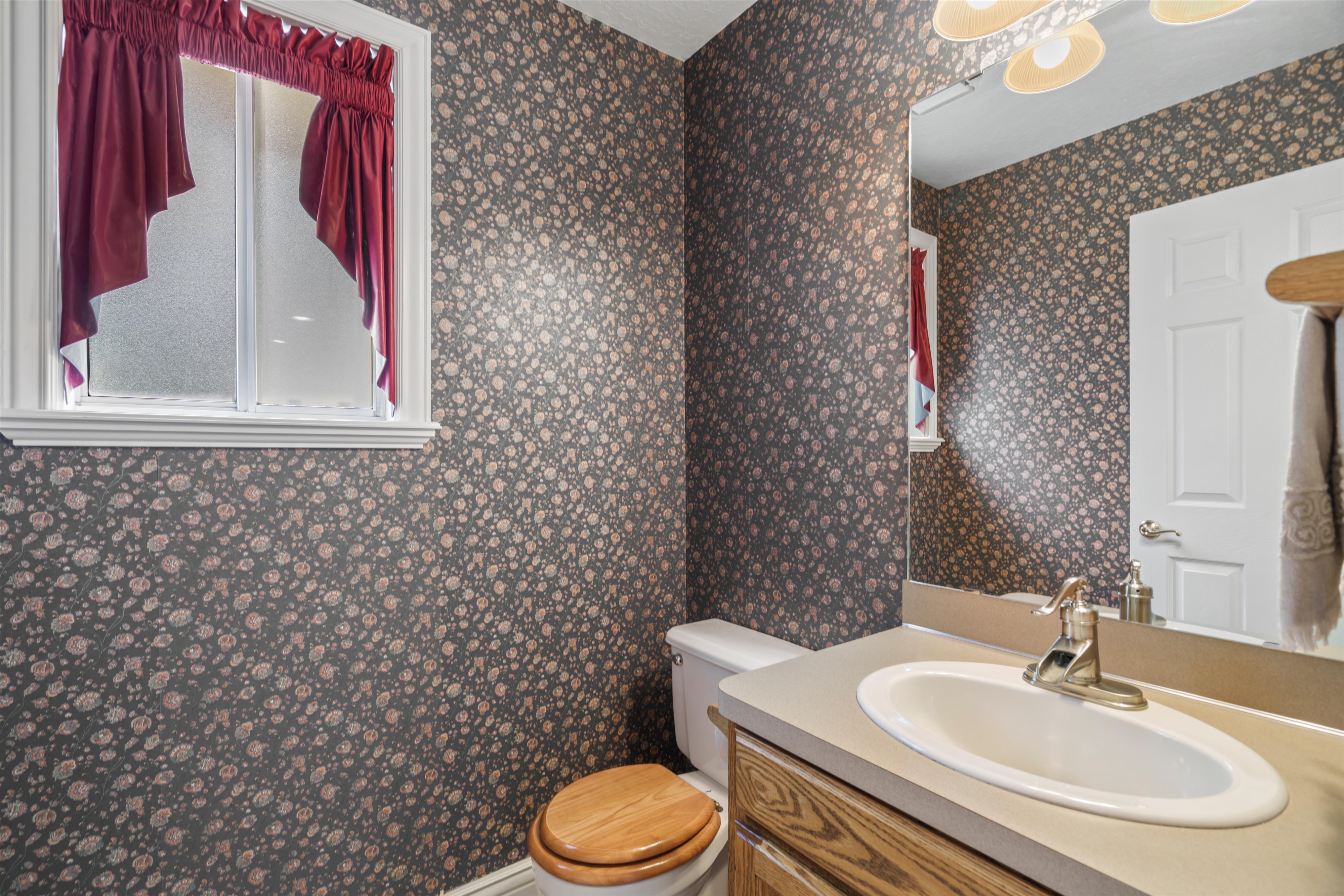 Bathroom featuring patterned wallpaper and a window with white trim