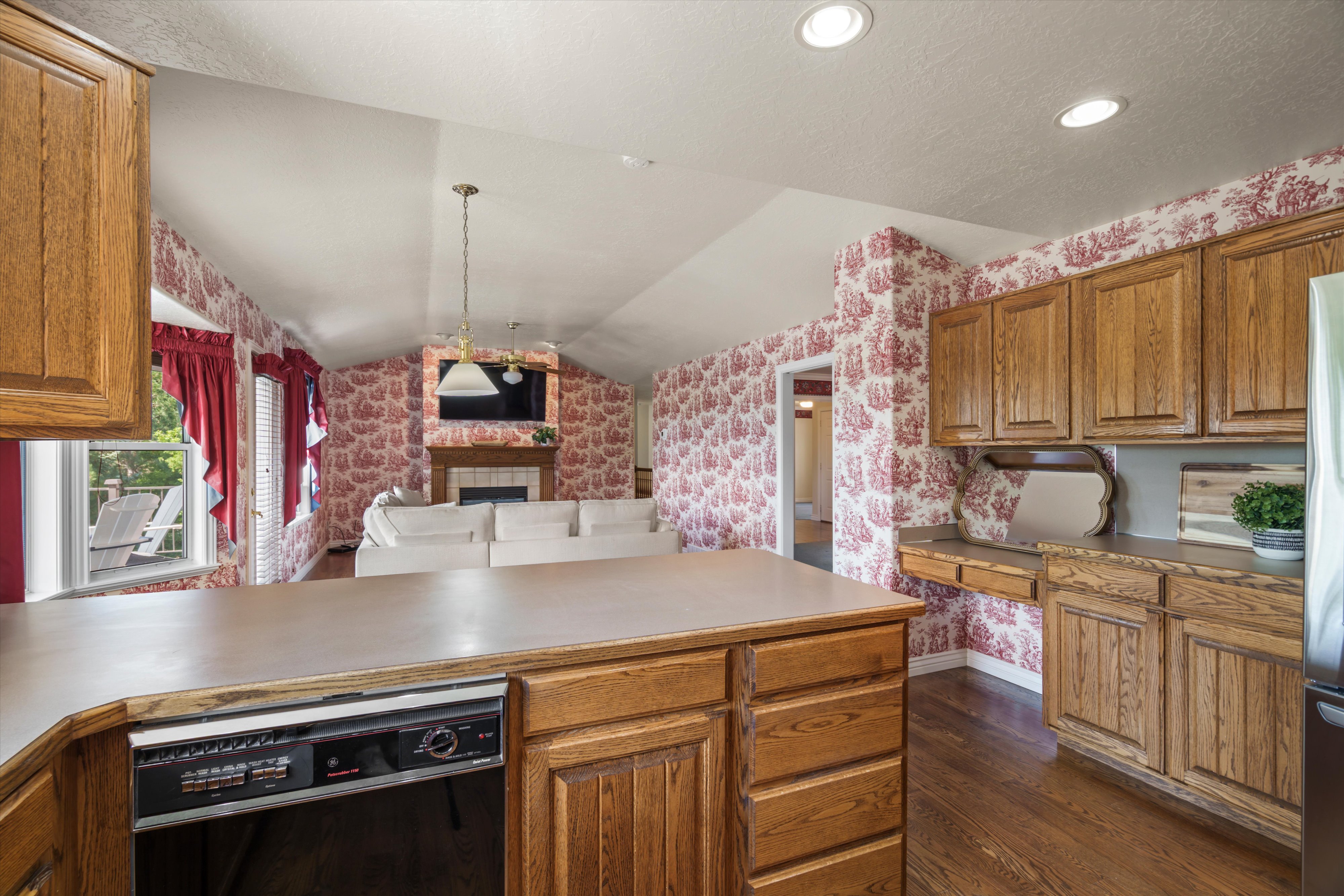 Kitchen island with integrated dishwasher, wood-finish cabinetry, and a built-in desk area