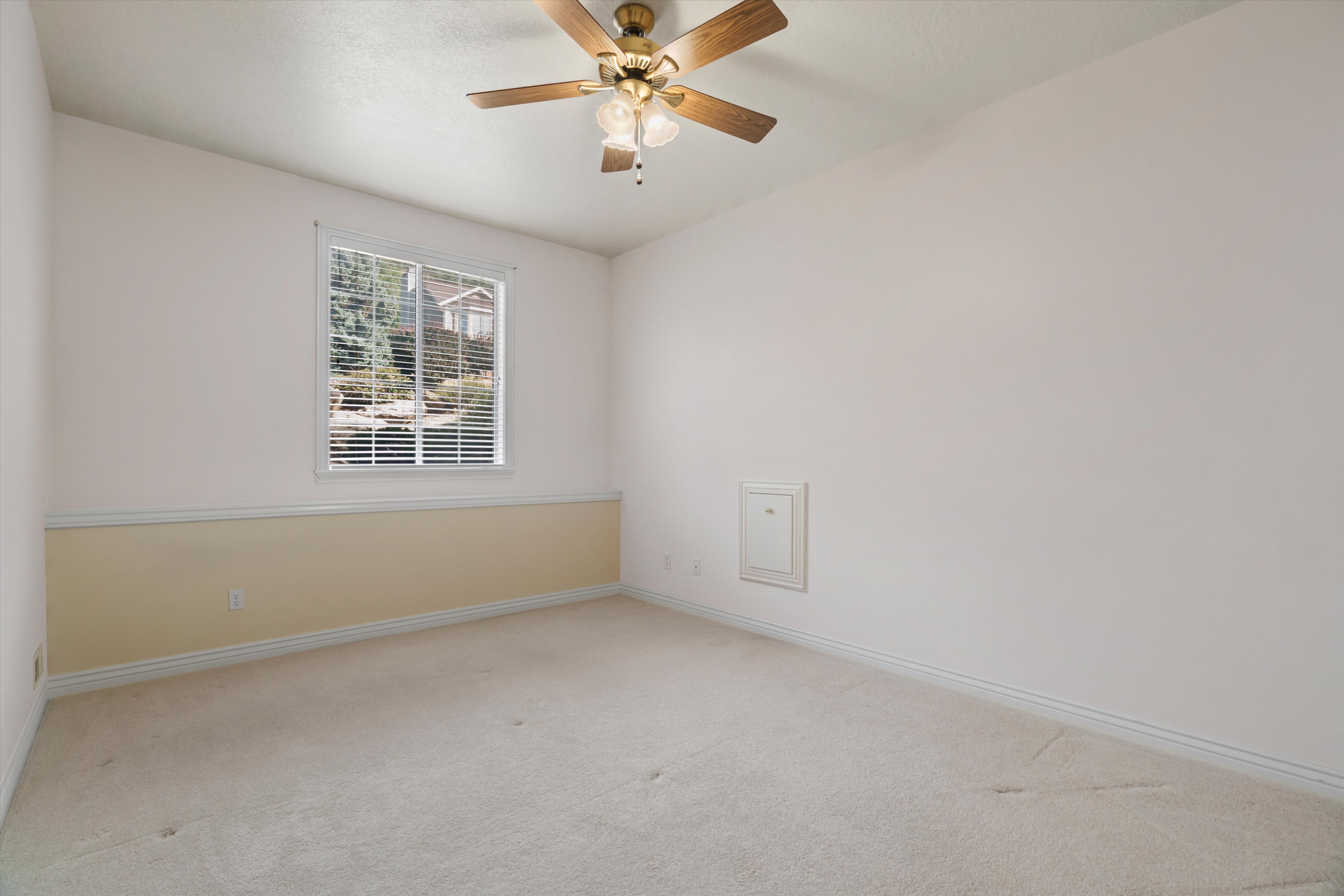 Room featuring a window with blinds, a ceiling fan with integrated lighting, a two-tone wall treatment, and light-toned carpeting