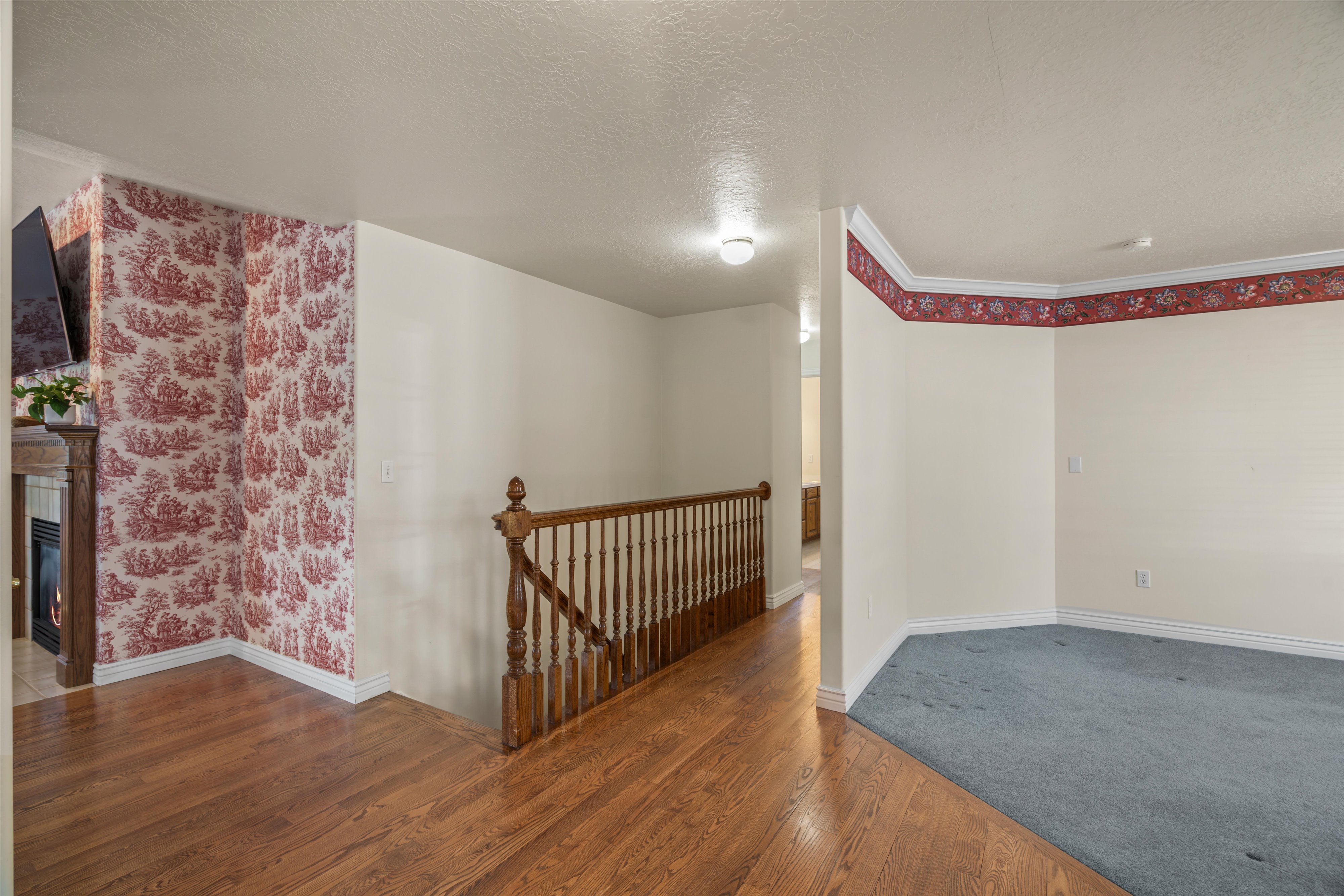 Wood-finish flooring throughout the main level, complemented by a staircase with wooden balusters and newel post