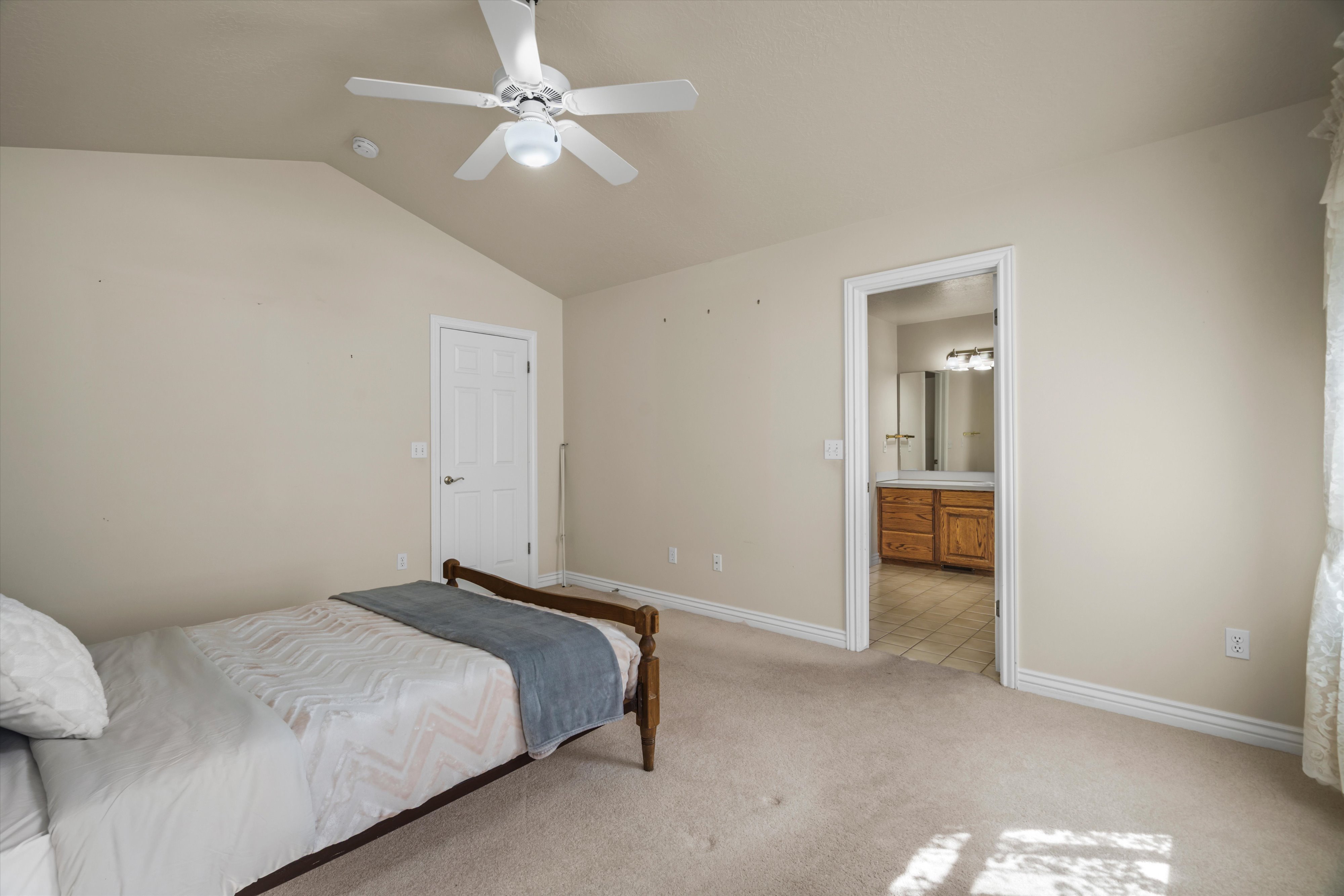Room featuring a vaulted ceiling with a ceiling fan, neutral wall tones, and plush carpet flooring