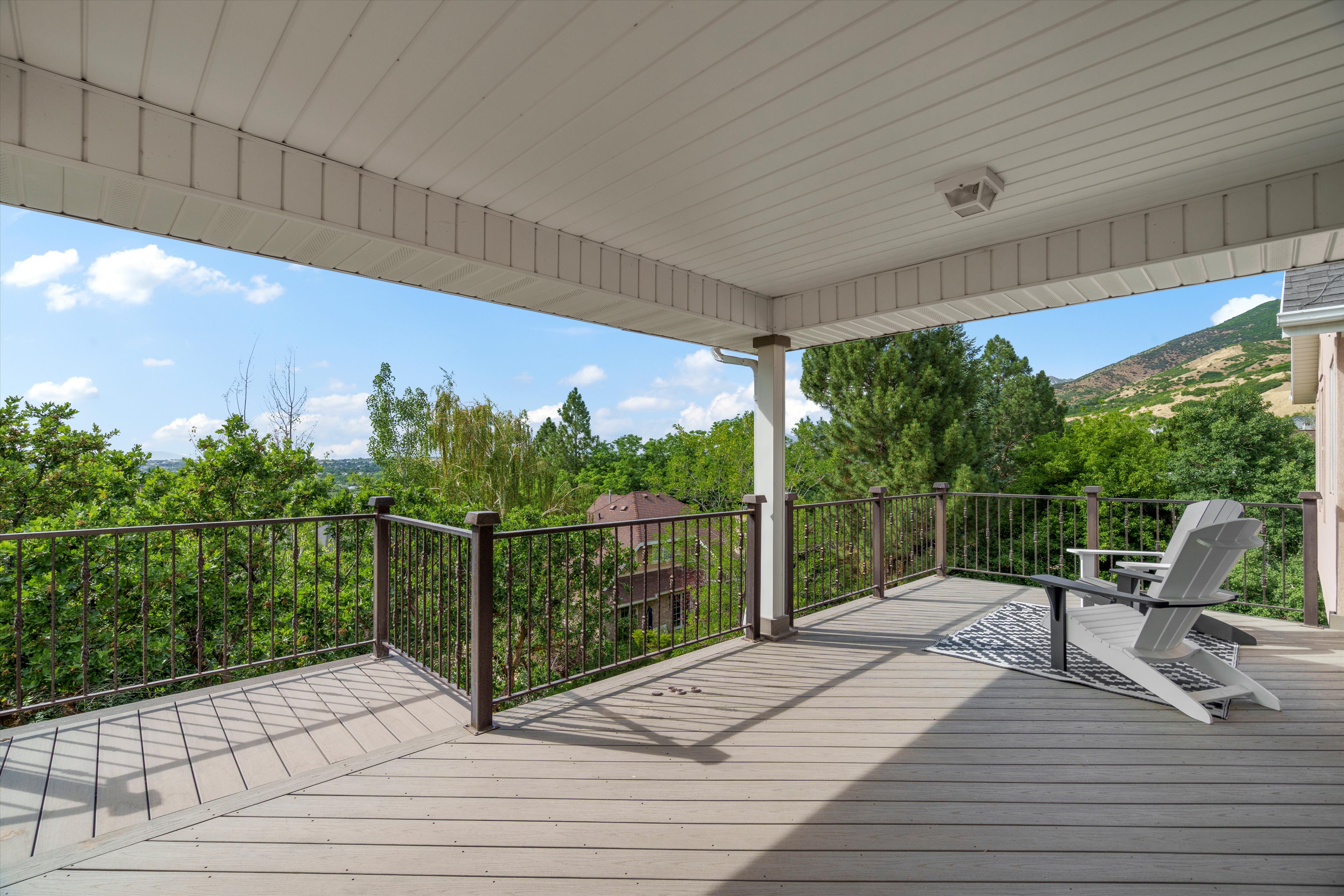 Spacious covered deck featuring composite decking, dark metal railings, and a white soffit ceiling