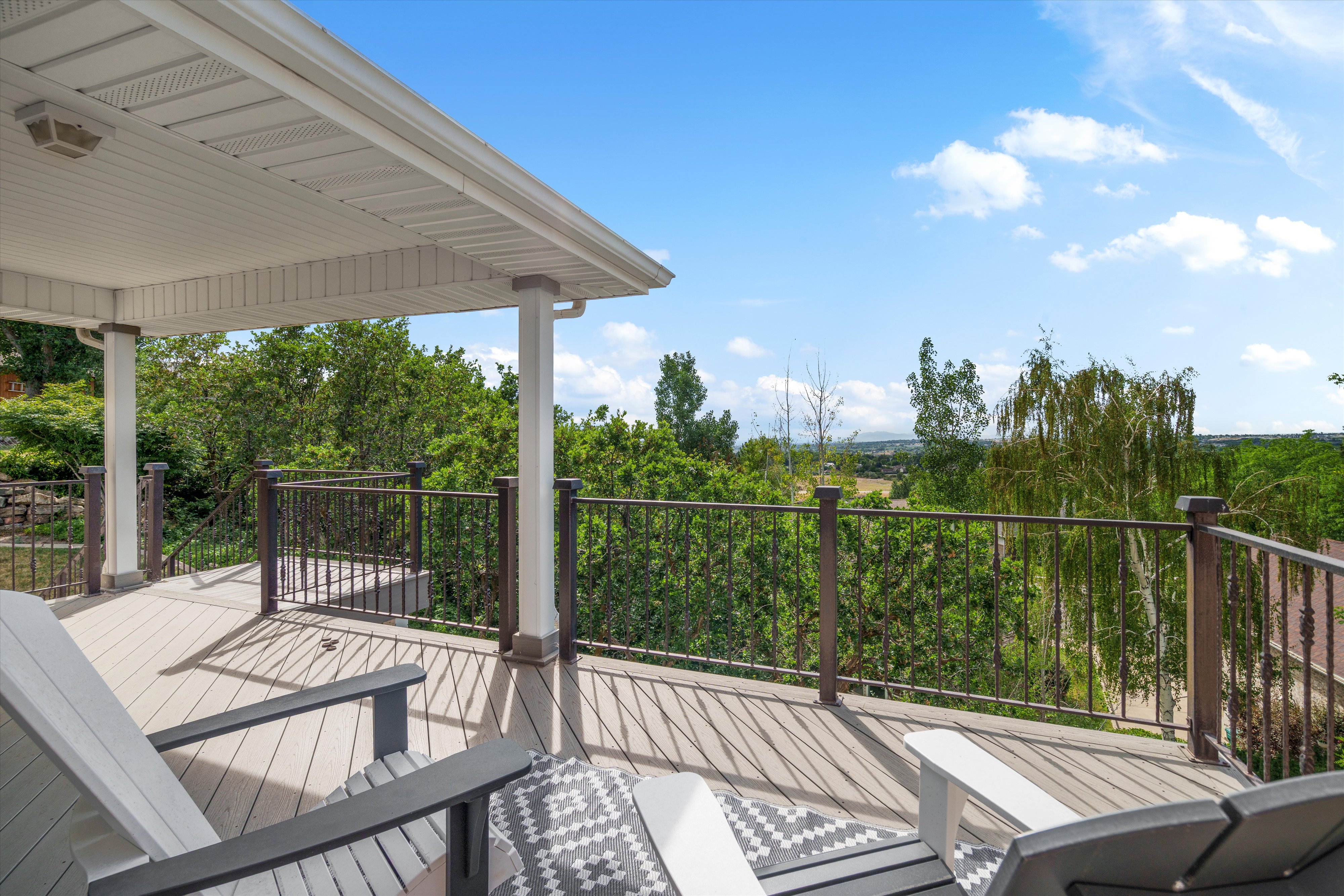 Expansive outdoor deck featuring a composite wood-finish surface, metal railings, and a covered patio area