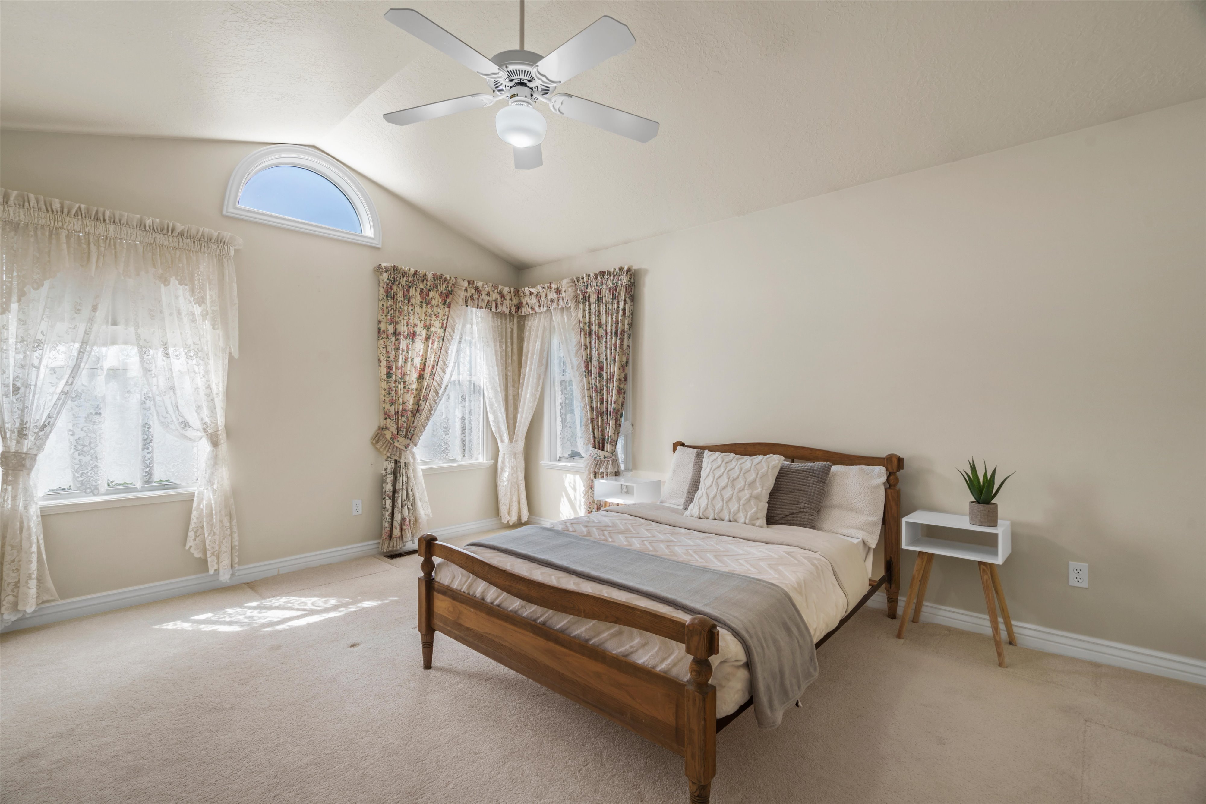 Bedroom featuring vaulted ceilings, a semicircular transom window, and a ceiling fan with integrated lighting
