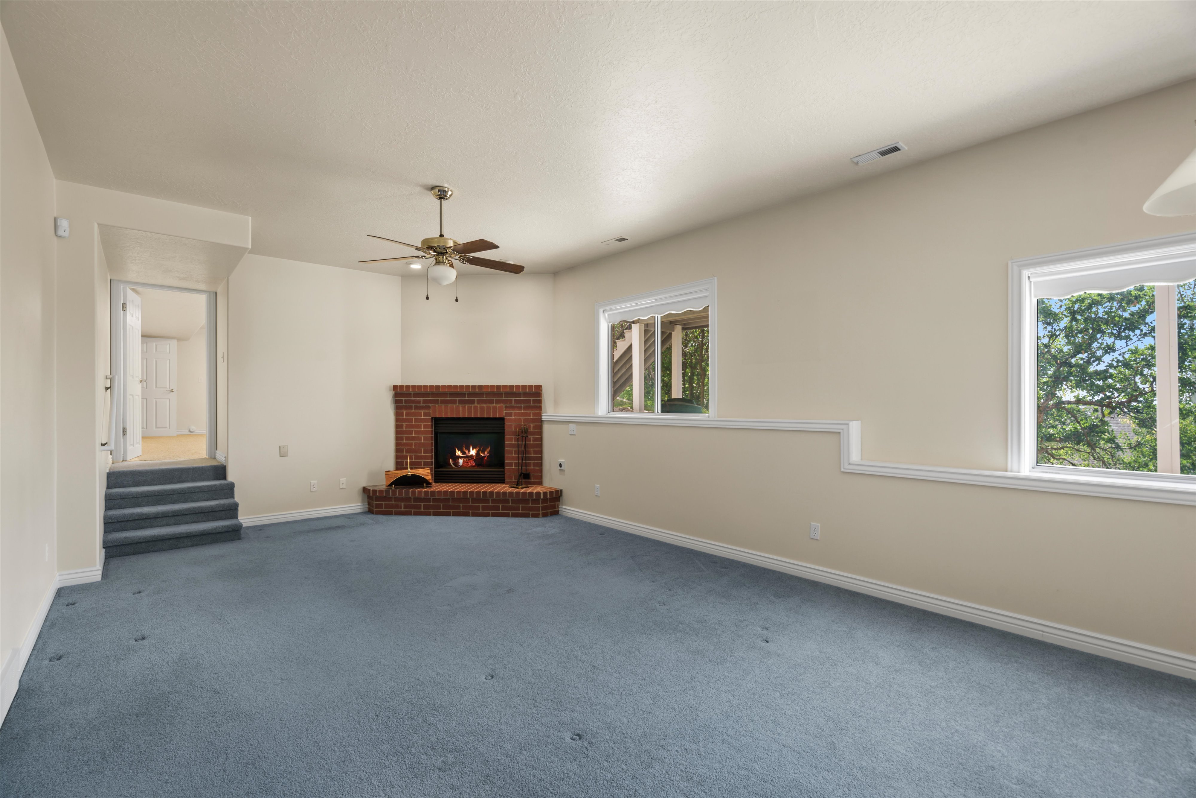 Spacious room featuring a brick fireplace, ceiling fan, and light-colored walls