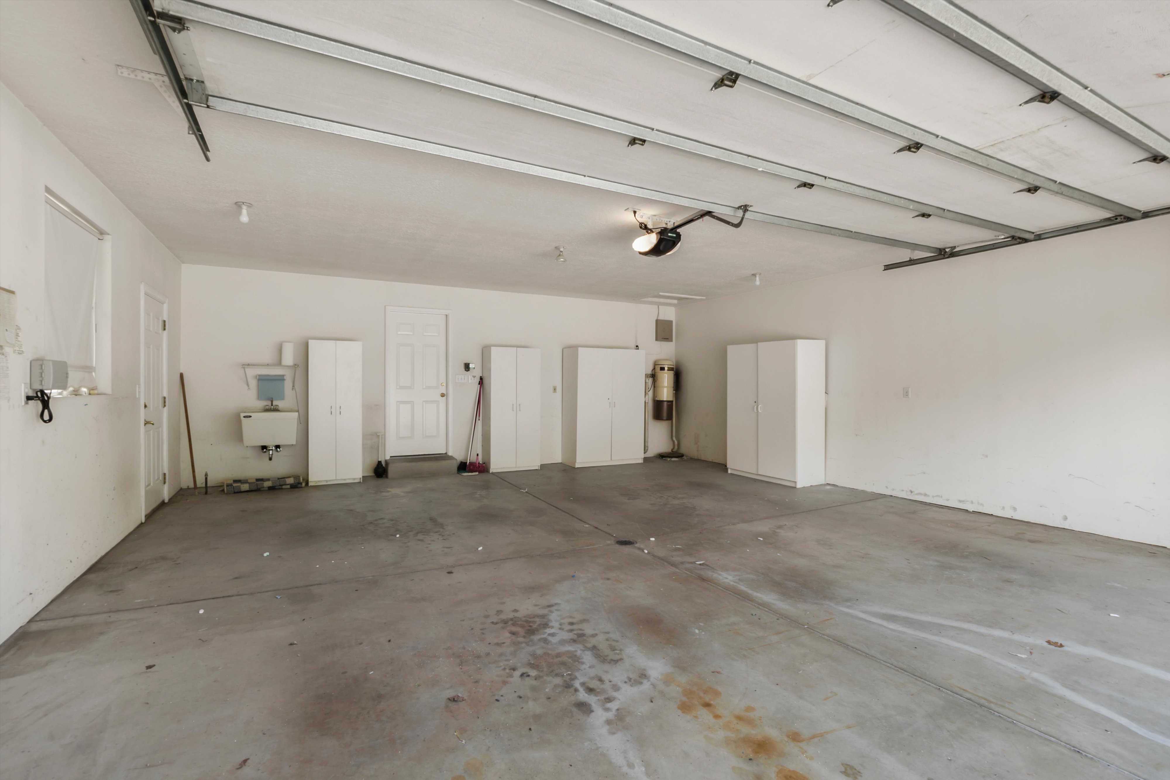 Spacious garage featuring a concrete floor, multiple storage cabinets, and a utility sink