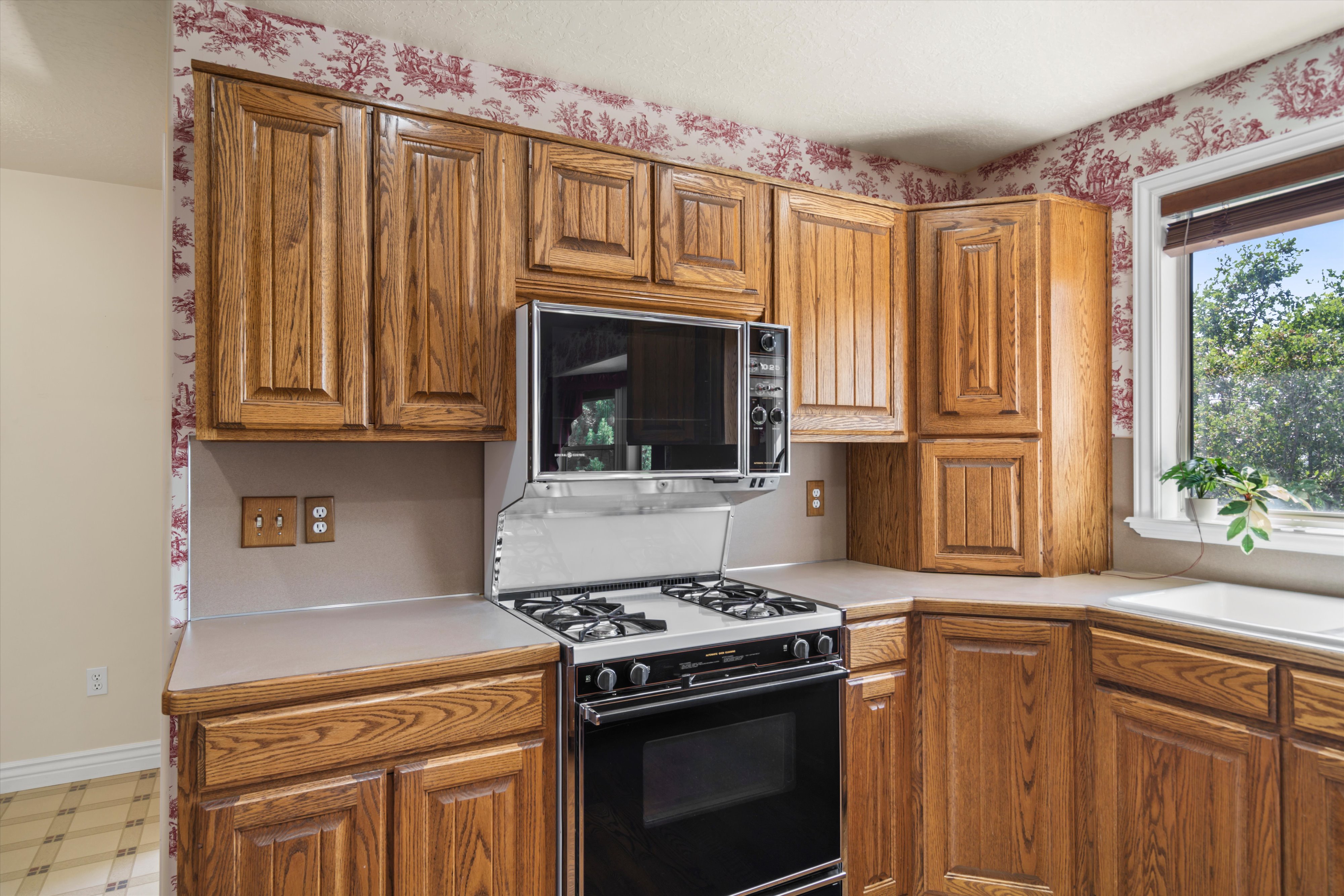 Kitchen area featuring wood cabinetry, integrated microwave, and a black range